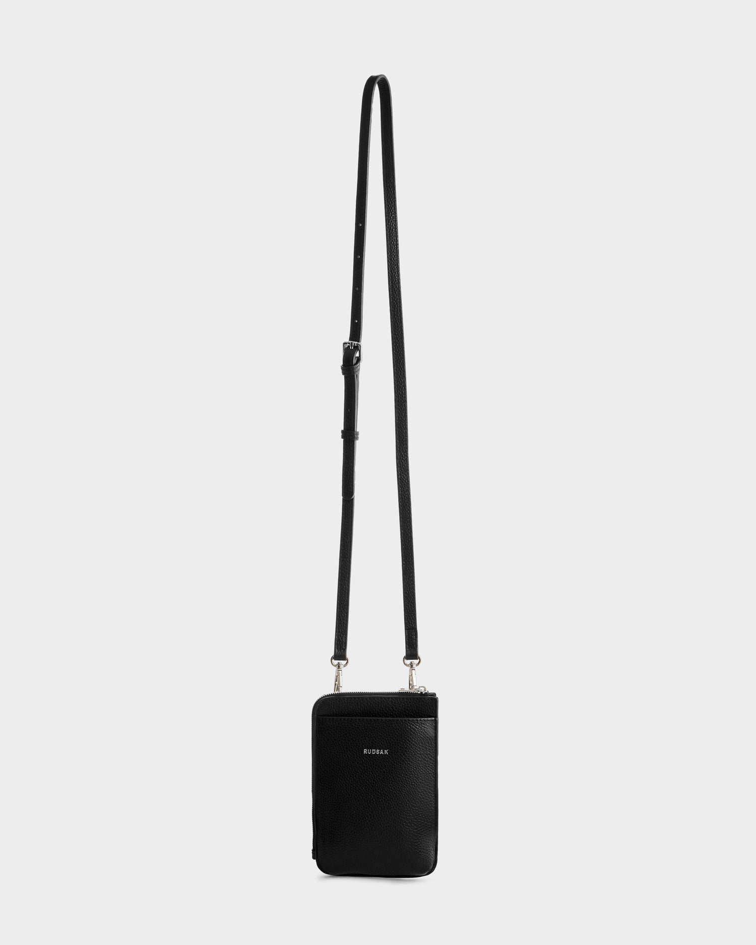 The Rudsak CELYN - L325514 Black is a small women’s leather crossbody bag with a minimalist design and long adjustable strap, shown against a plain light gray background.
