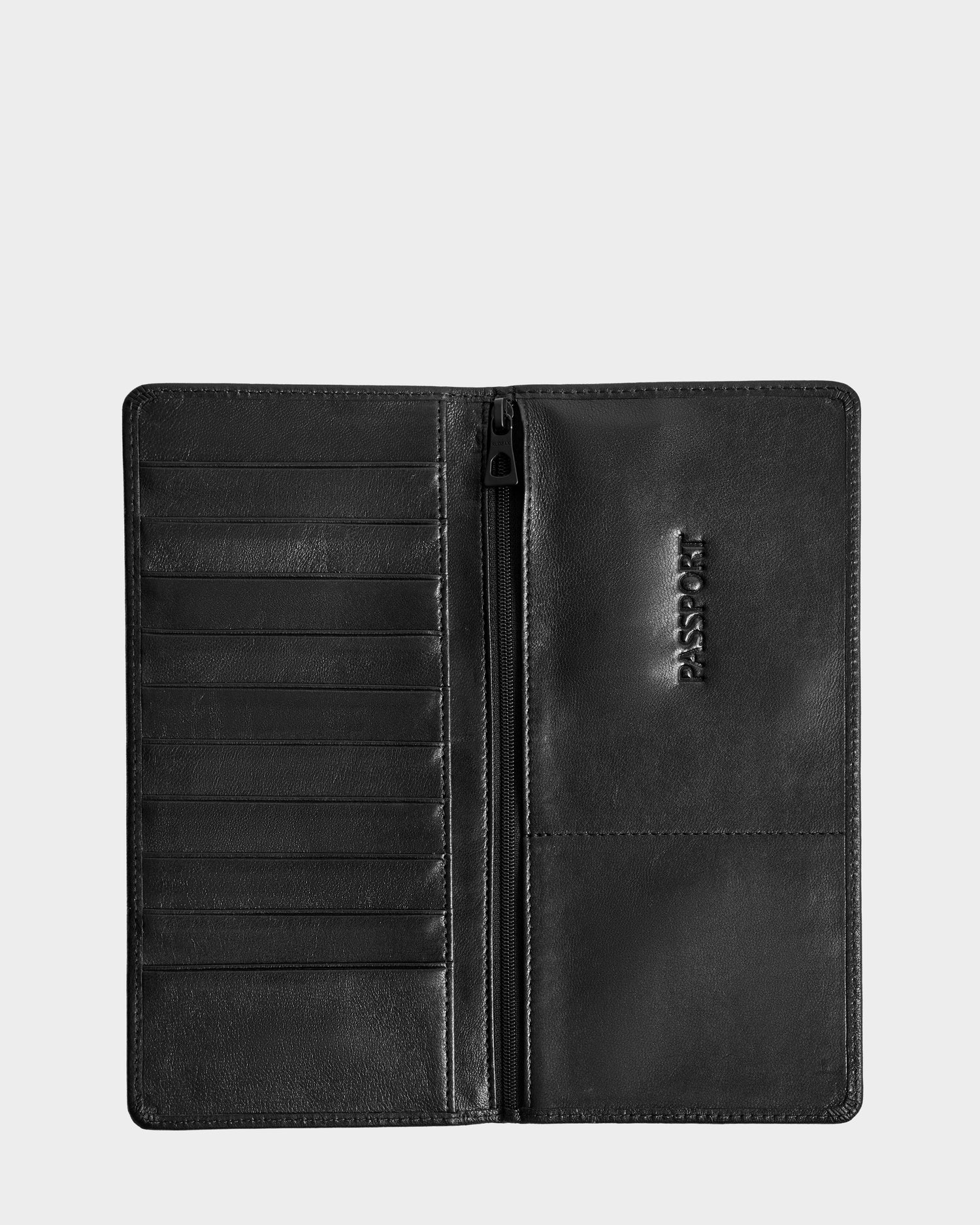The CLEO - 9425522 Black by Rudsak is an open black leather passport holder with multiple card slots, a zippered center compartment, and a PASSPORT-embossed slot—making it the perfect travel accessory.