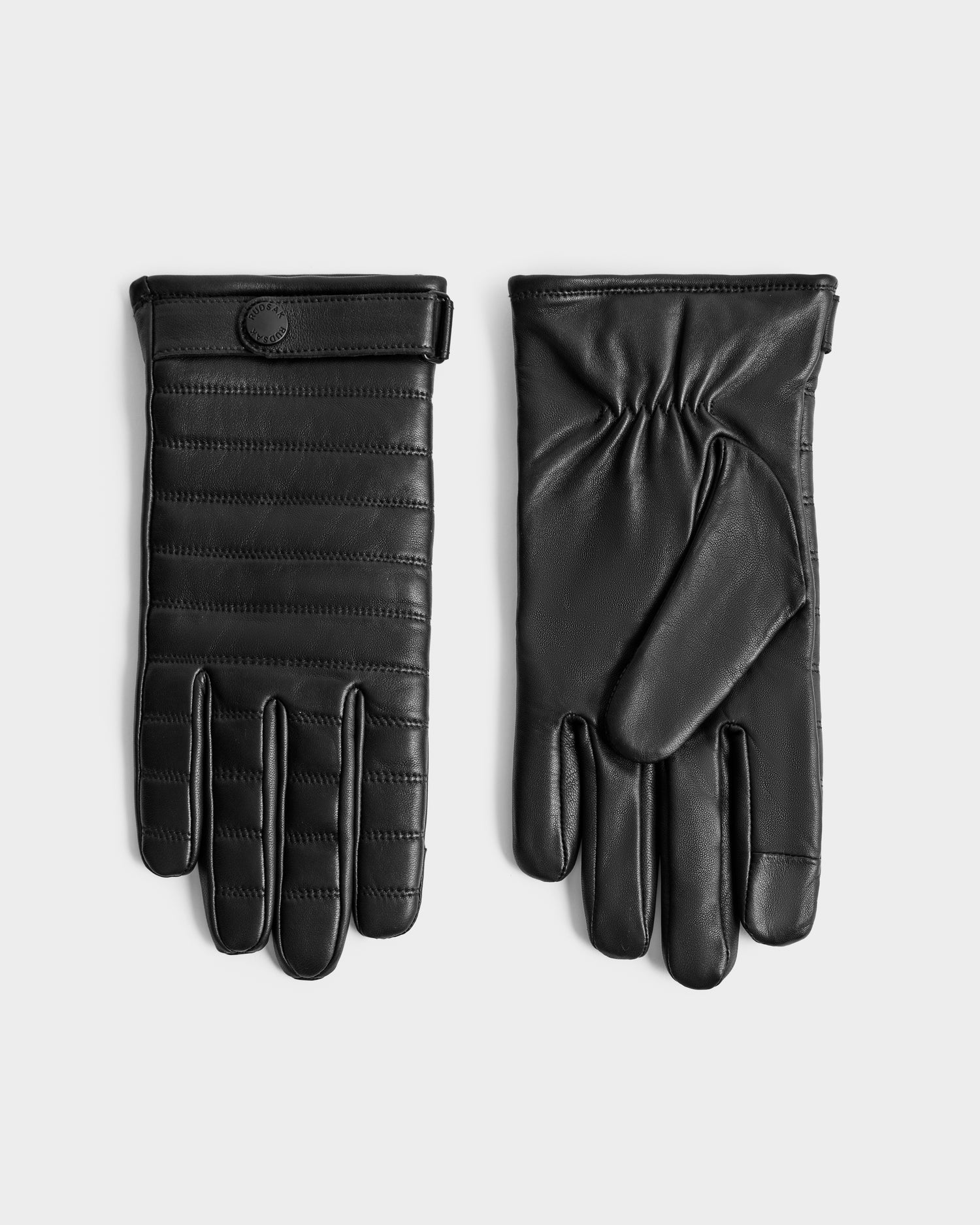 The Rudsak CORTES - 6425036 Black leather gloves are shown on a flat surface, one displaying the front and the other the back. They feature stitched detailing and a snap button at the wrist—ideal as winter accessories.