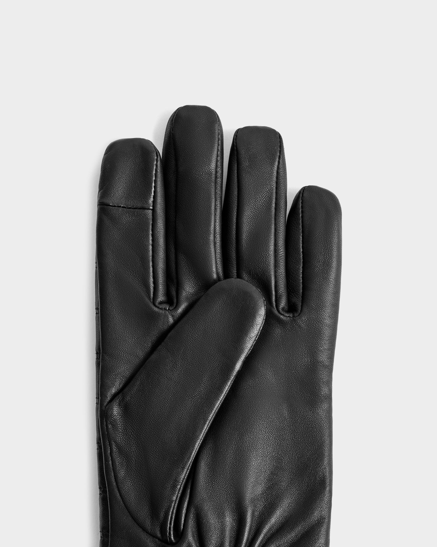 The Rudsak CORTES - 6425036 Black leather glove, perfect for winter, is shown palm up with the thumb crossed over the palm on a plain light gray background.