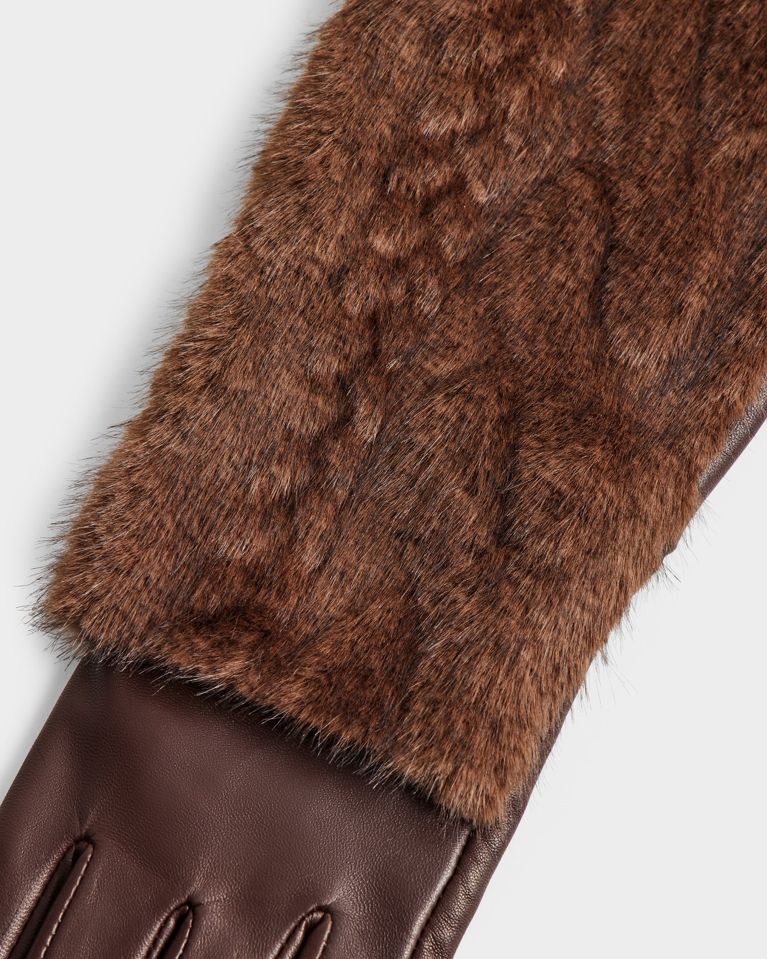 Close-up of the Rudsak COVE - 8425533 Mocha glove, featuring a brown faux fur upper and smooth leather lower section with fine stitching that highlights the detailed material contrast.