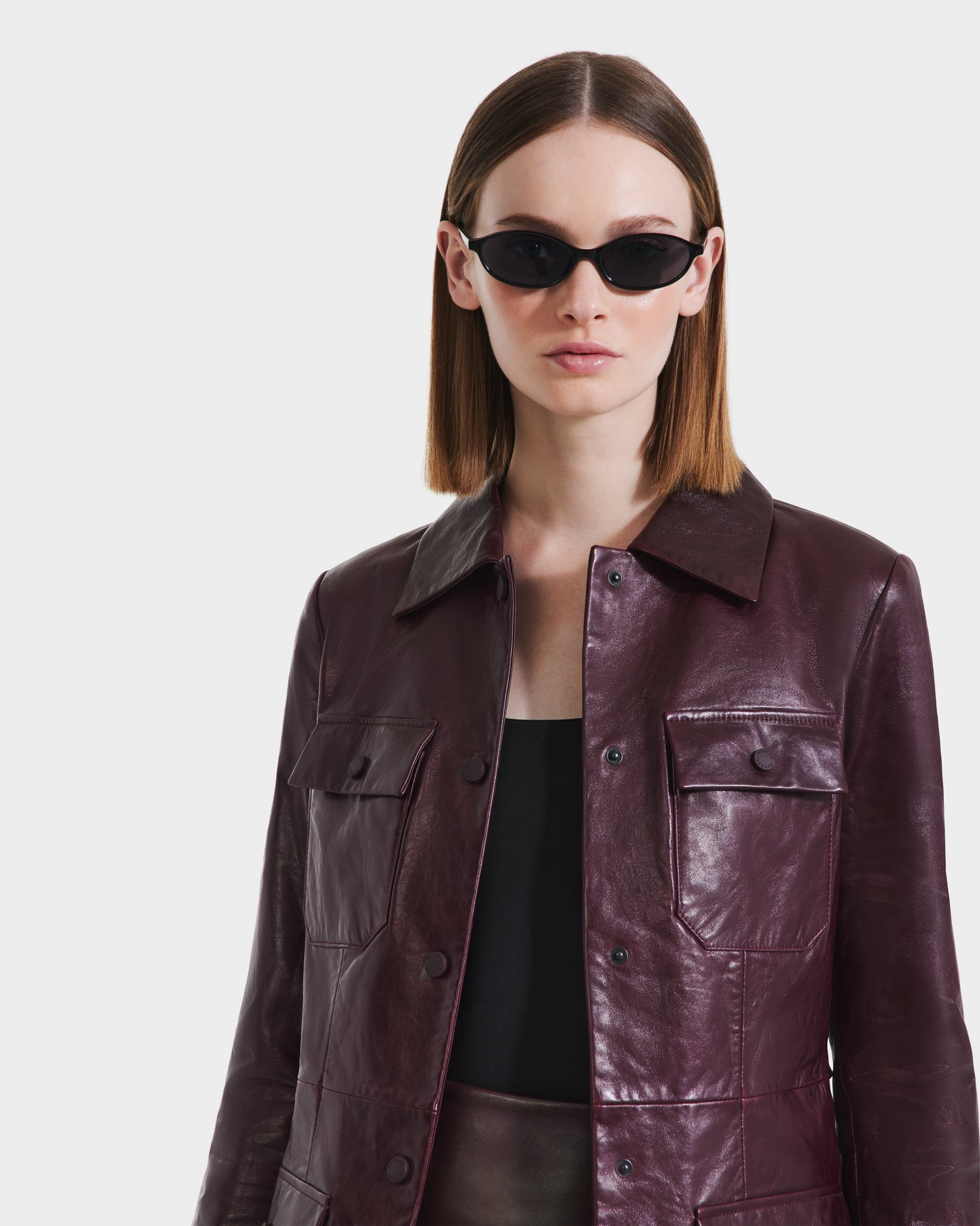 A woman wearing sunglasses and the Rudsak DANICA - 8125025 Bordeaux women’s leather jacket with a tailored design.