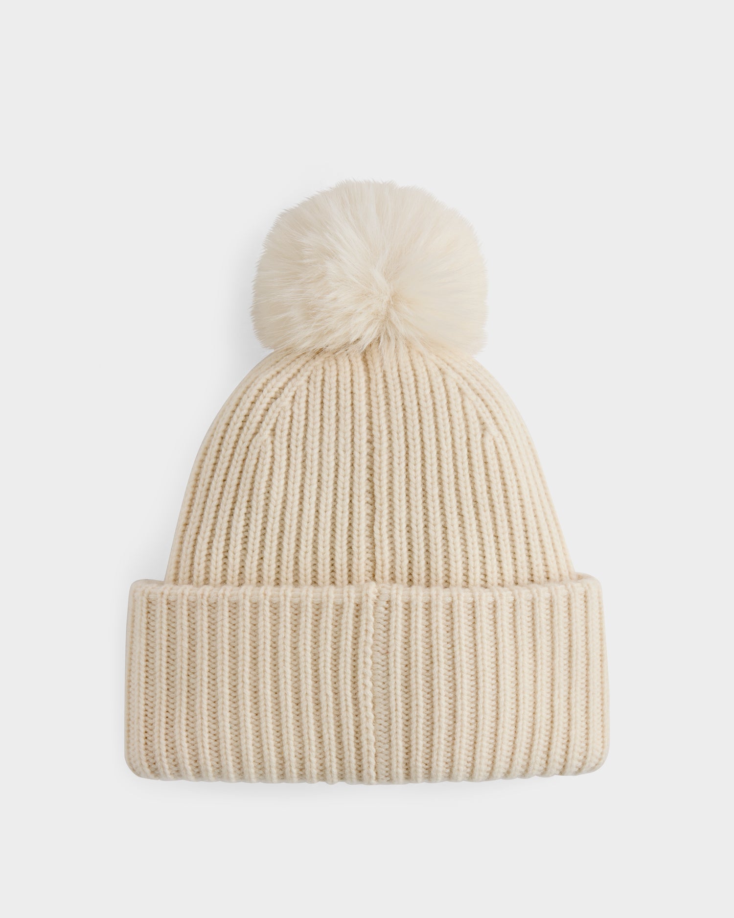 The DARA - 8425019 Vanilla by Rudsak is a cream-colored women’s knit winter hat featuring a folded brim and a fluffy faux fur pom pom, shown on a white background.