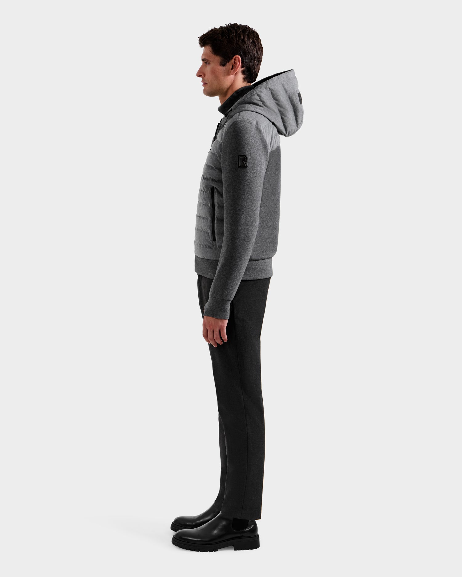 A man stands in profile against a plain white background, wearing the Rudsak DEE W - 6125570 Heather Charcoal jacket, dark pants, and black boots.