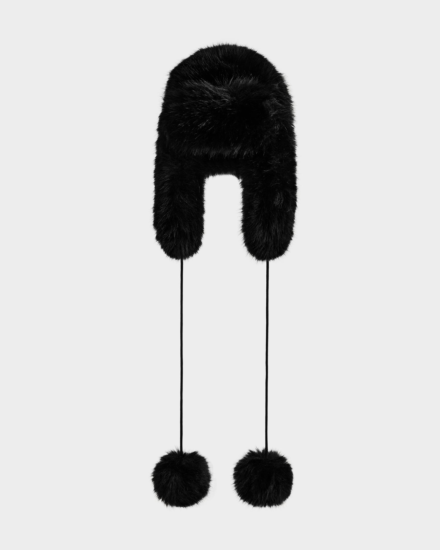 The DEMI - L425539 Black by Rudsak is a women's faux-fur aviator hat with earflaps and two long pom-pom strings, shown on a light gray background. This chic winter accessory blends cozy comfort with stylish design.
