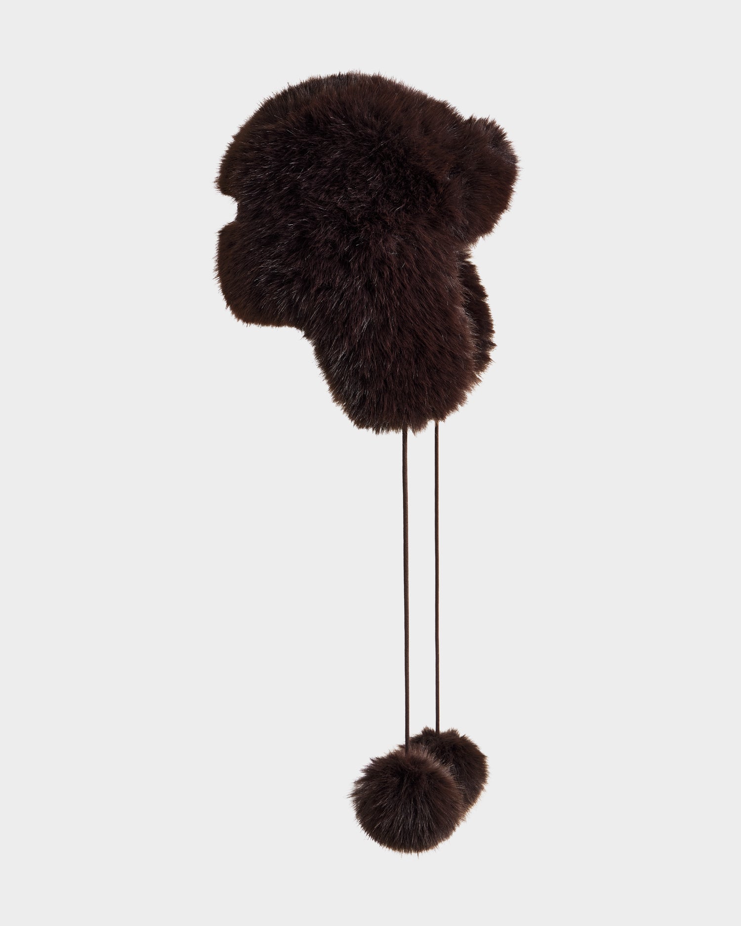 The DEMI - L425539 Espresso by Rudsak is a dark brown women’s faux-fur aviator hat with ear flaps and two long fur pom-pom strings, shown against a light gray background.