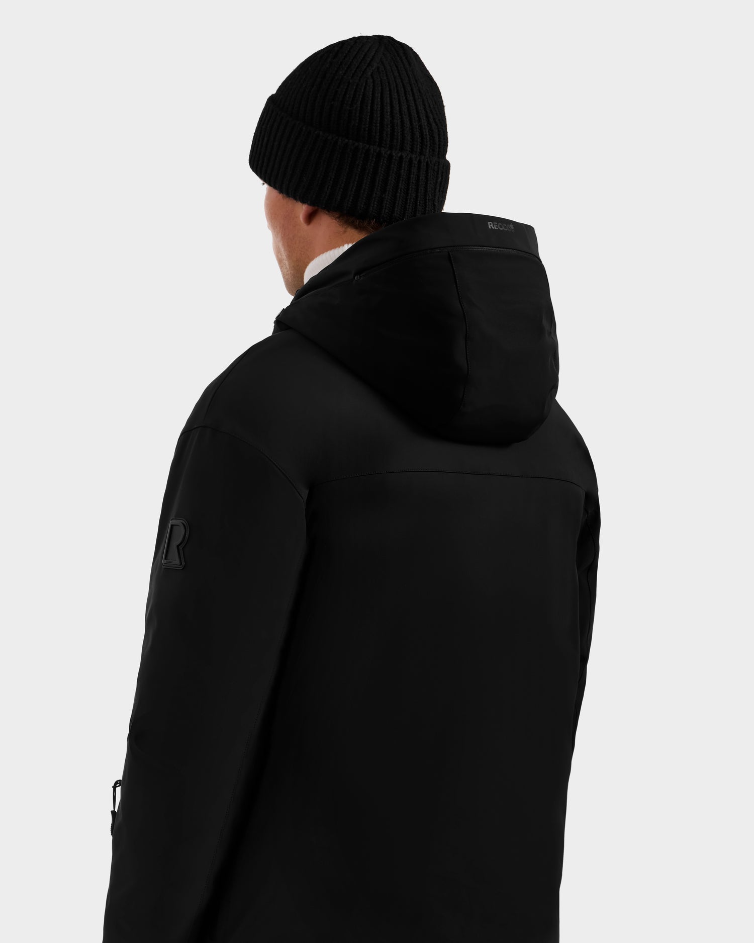 A person is shown from behind in a black beanie and the Rudsak ETHAN - 6125589 Black men’s hooded ski jacket against a plain light background.