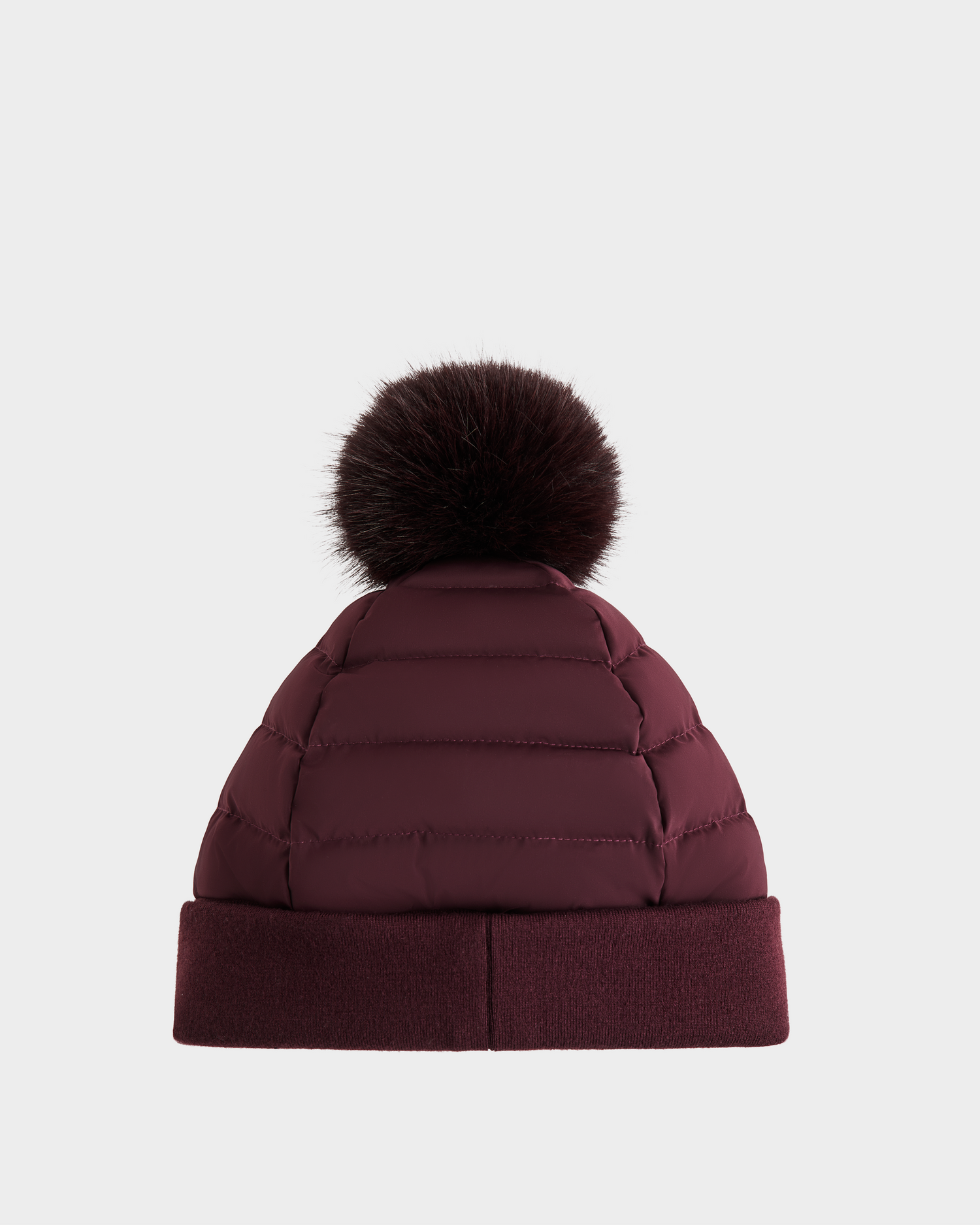 The Rudsak GALA - 8424514 Bordeaux is a maroon quilted winter hat with a folded brim and a large dark brown faux fur pom-pom, shown on a plain white background.