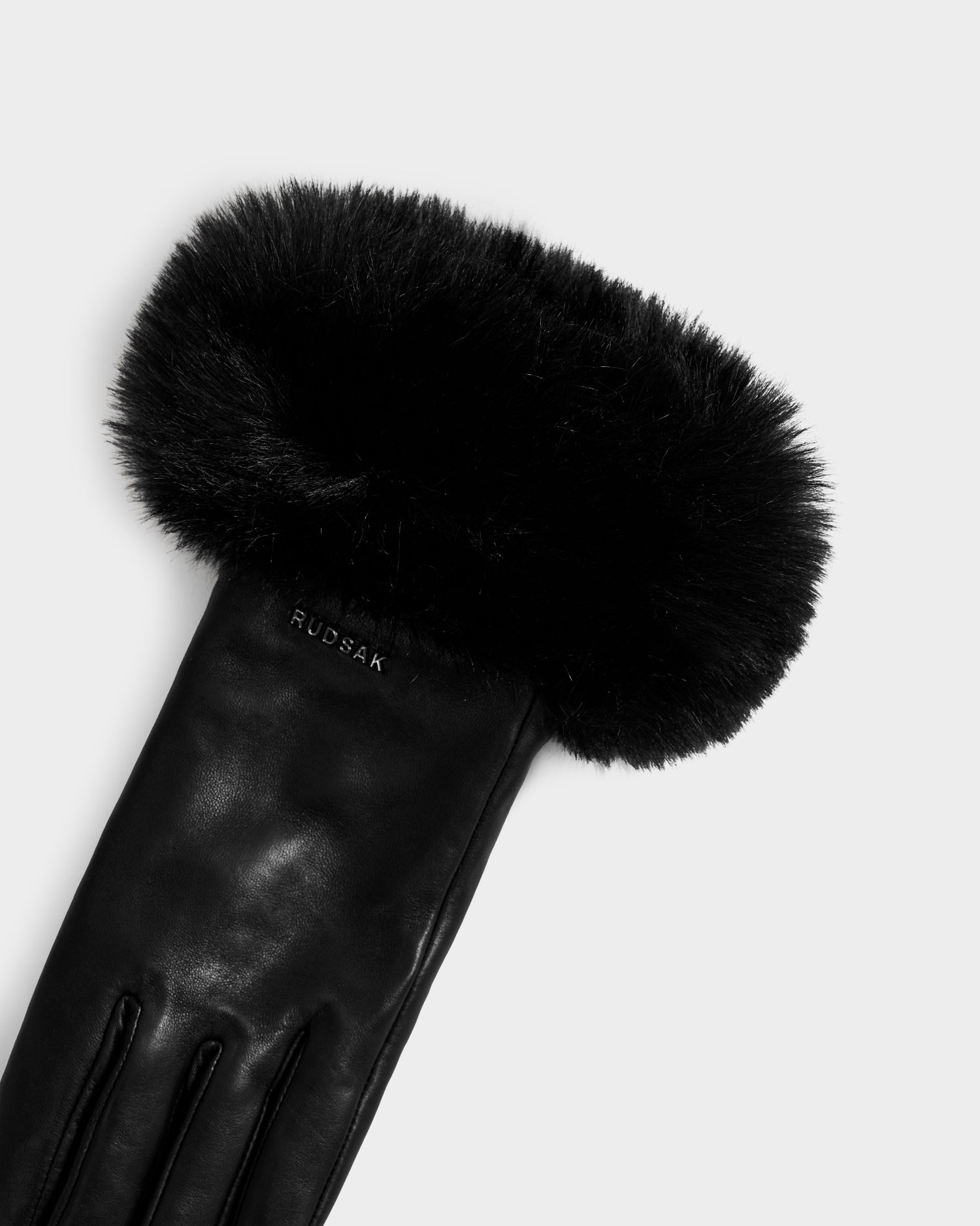 The Rudsak GERRY - L425550 Black women’s glove features lamb leather and a fluffy faux-fur cuff, with the Rudsak name embossed on the wrist. Shown against a white background.