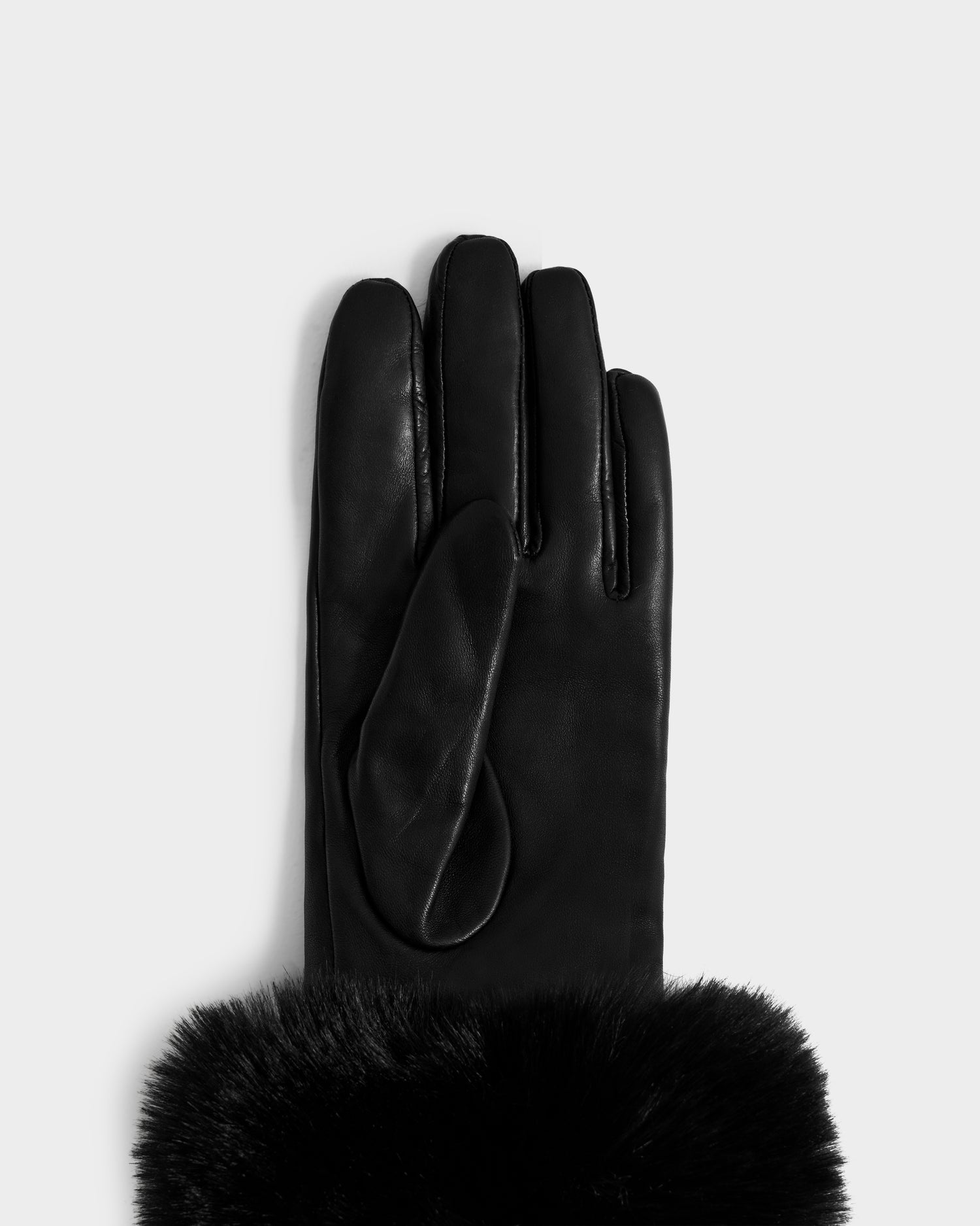 The Rudsak GERRY - L425550 Black women's leather glove, featuring a soft black faux-fur cuff, is displayed palm down on a light grey background.