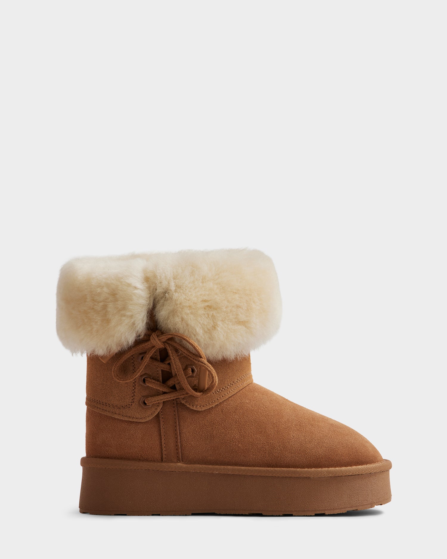 The Rudsak INESA - L225026 Tan is a women’s suede platform boot with a cream fur cuff, wool lining, side lace-up detail, and a flat lightweight sole, displayed against a plain light background.