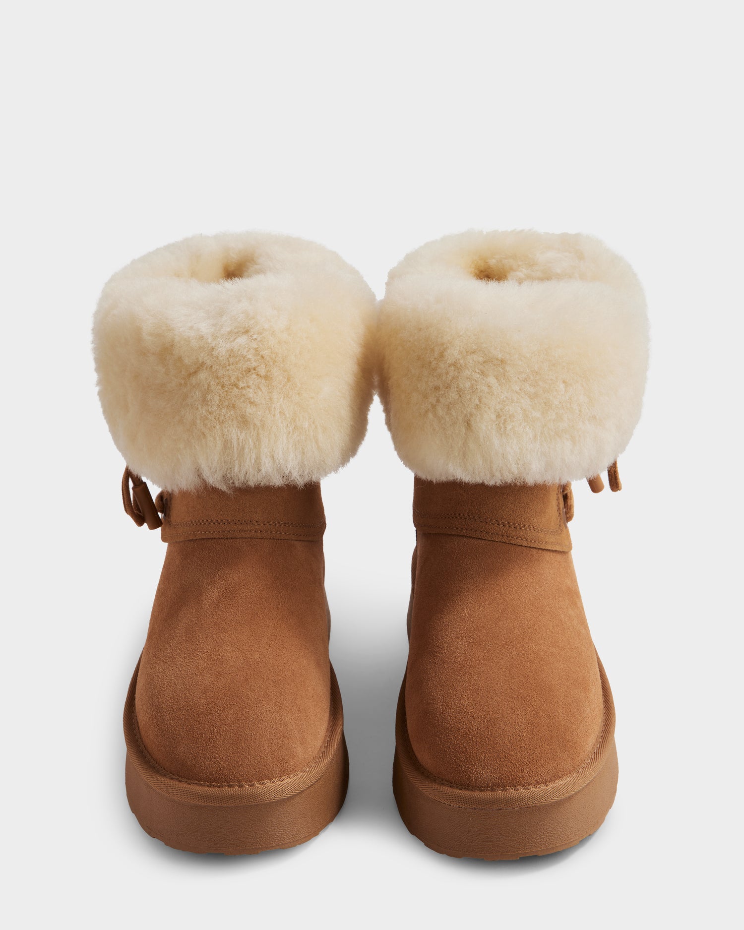 The Rudsak INESA - L225026 Tan women’s suede platform boots feature thick cream shearling cuffs, rounded toes, and a lightweight sole; shown upright on a white background.