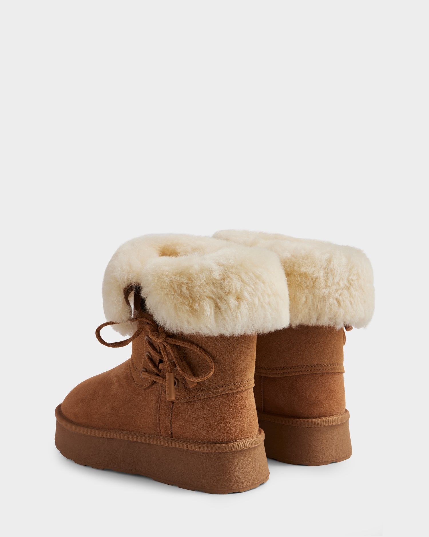 The Rudsak INESA - L225026 Tan women’s suede platform boots in brown feature cream-colored wool lining, laces, and a lightweight platform sole. Shown from the back and side for a stylish look.