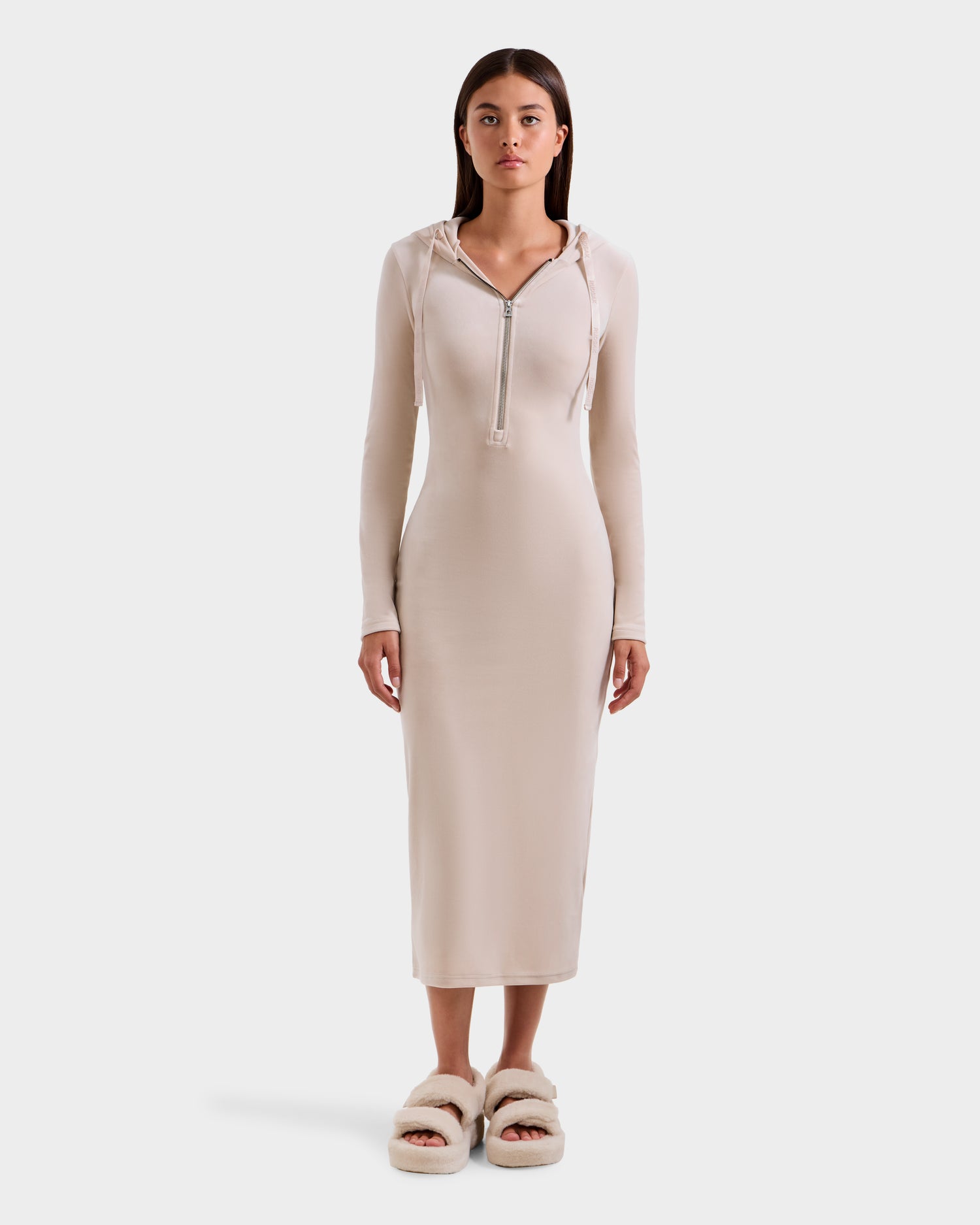 A woman faces forward in a Rudsak ISABELLA - L525502 cream velour hooded dress, mid-calf length, paired with fluffy cream slippers against a plain white background.