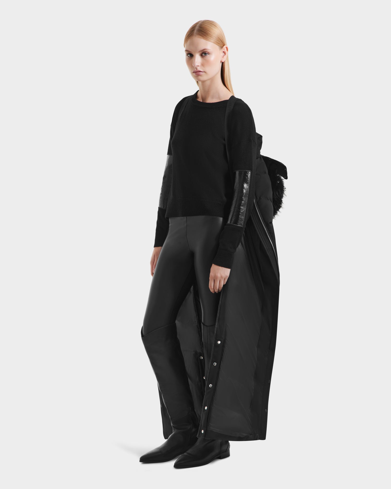 A woman with straight blonde hair models the Rudsak IZABELLA H - 8125644 Black jacket over a black top, leather pants, and shoes, posed against a plain white background.