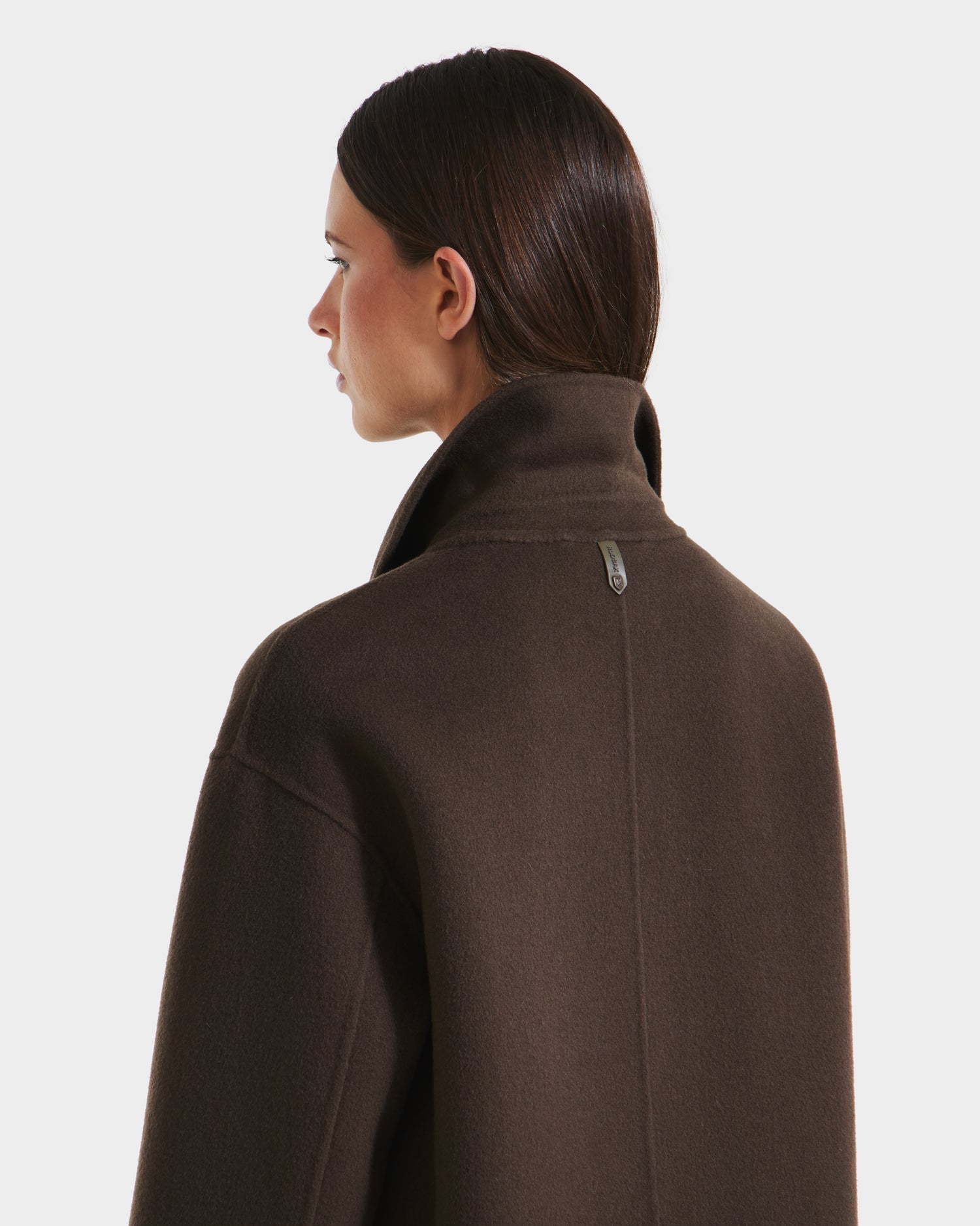 A woman with straight, dark brown hair is seen in profile from behind, wearing the Rudsak JADE - 8125673 Army women’s wool overcoat against a plain white background.