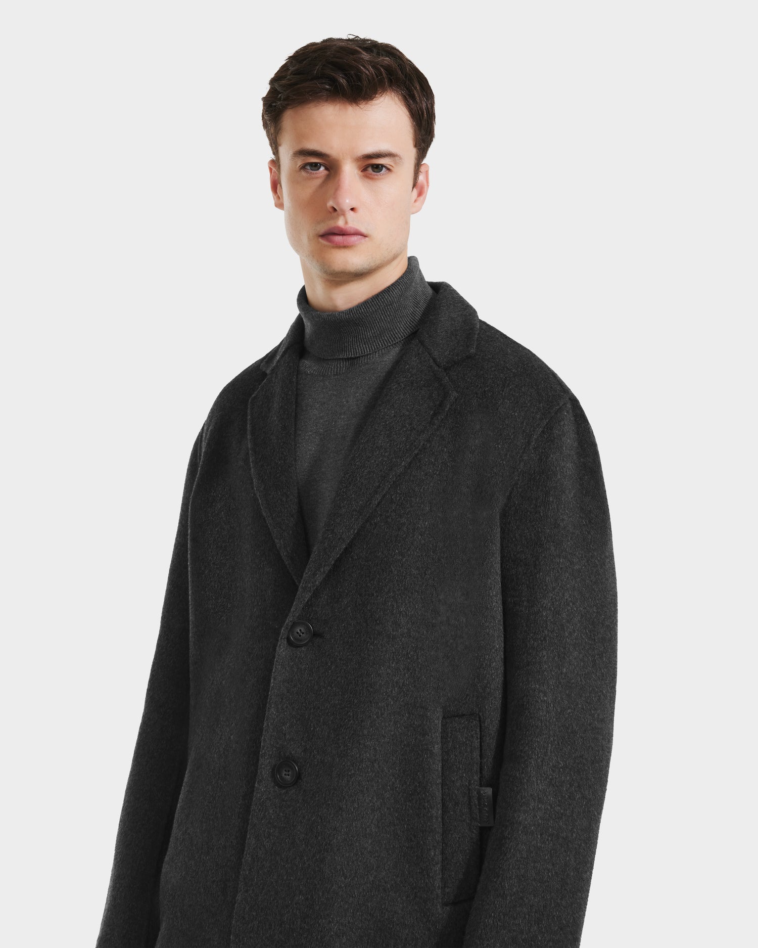 A man wears the Rudsak JEREMIAH - 6125509 Grey wool-blend coat with a matching turtleneck, standing against a plain background. This cold-weather staple includes a removable down-insulated dickie for warmth and versatility.