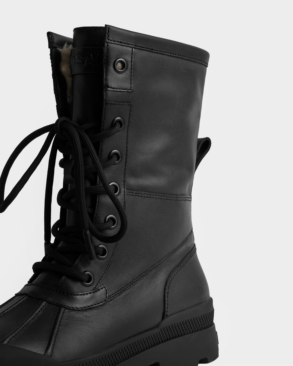 A detailed shot of the Rudsak JESI - 8225026 Black combat boot features visible stitching, metal eyelets, and a rugged sole, set against a plain white background.