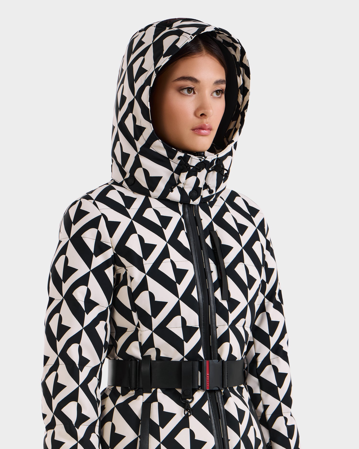 A woman wearing the Rudsak JOANNA P - 8125623 Vanilla Monogram women’s down ski jacket stands against a plain white background.