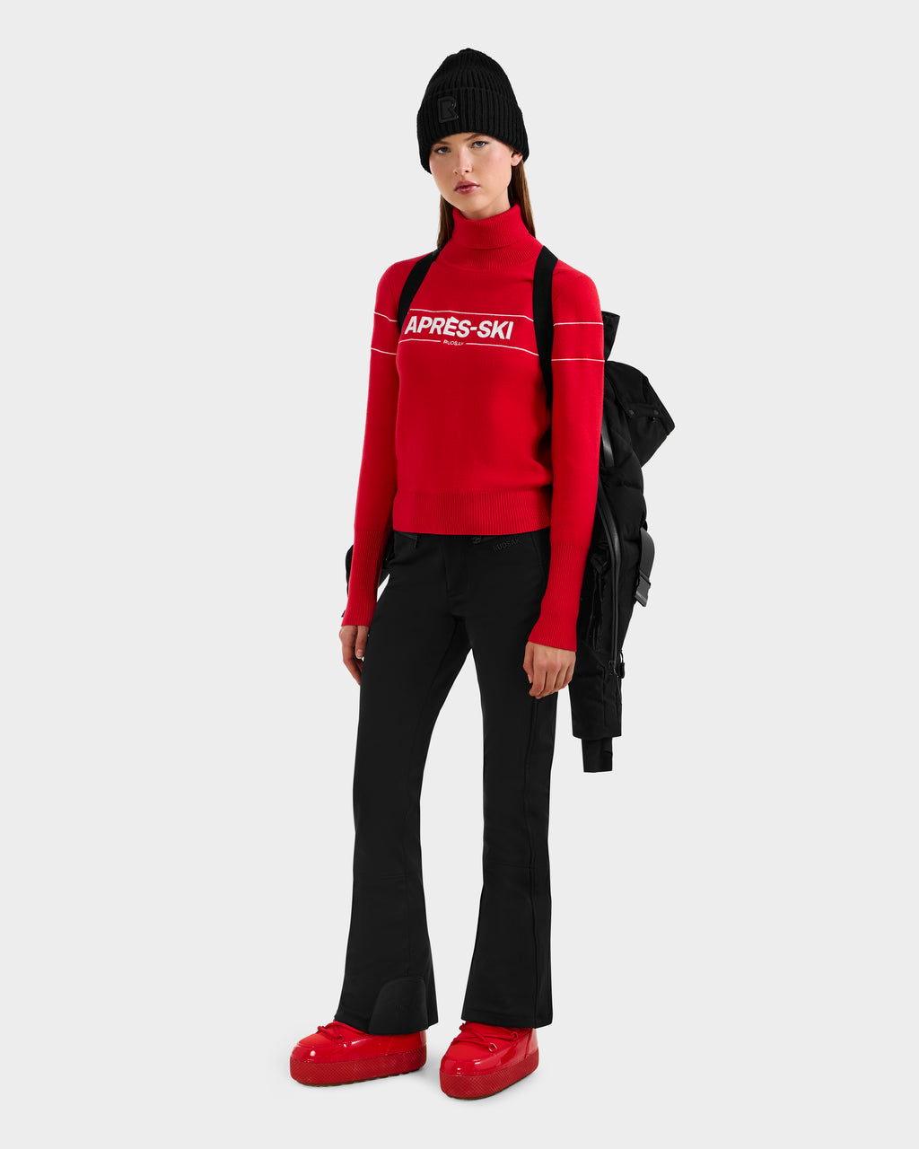 A woman in a black hat and red sweater is ready for winter, showcasing the Rudsak JOANNA - 8124788 Black women's down ski jacket with removable belt.