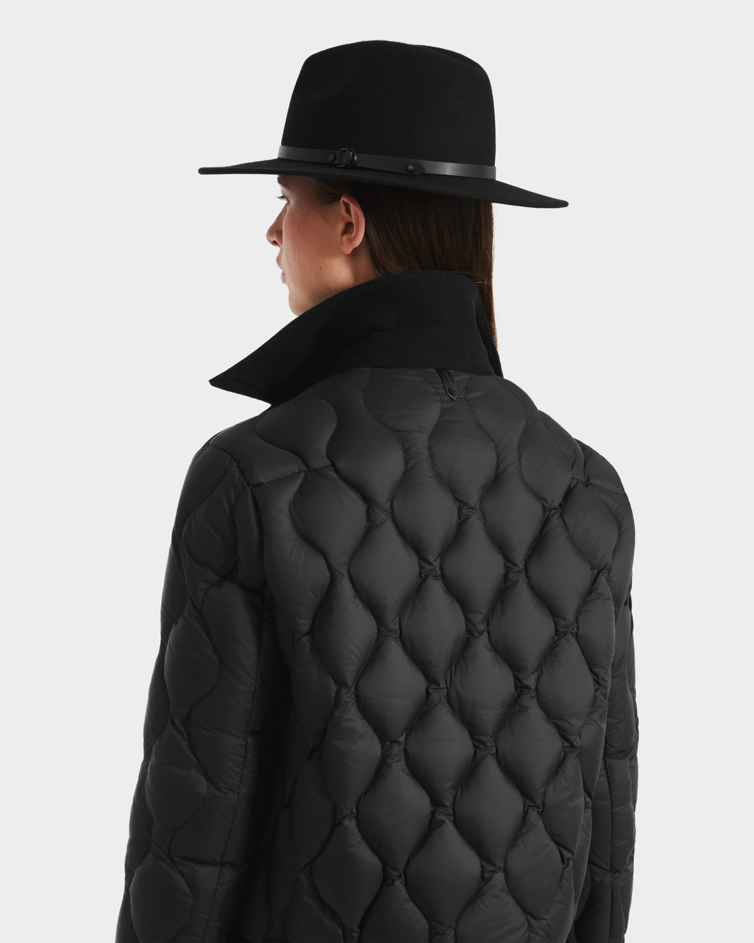 A person in a black wide-brim hat and the Rudsak JOLIE - 8125036 Black jacket is seen from behind against a plain light background.