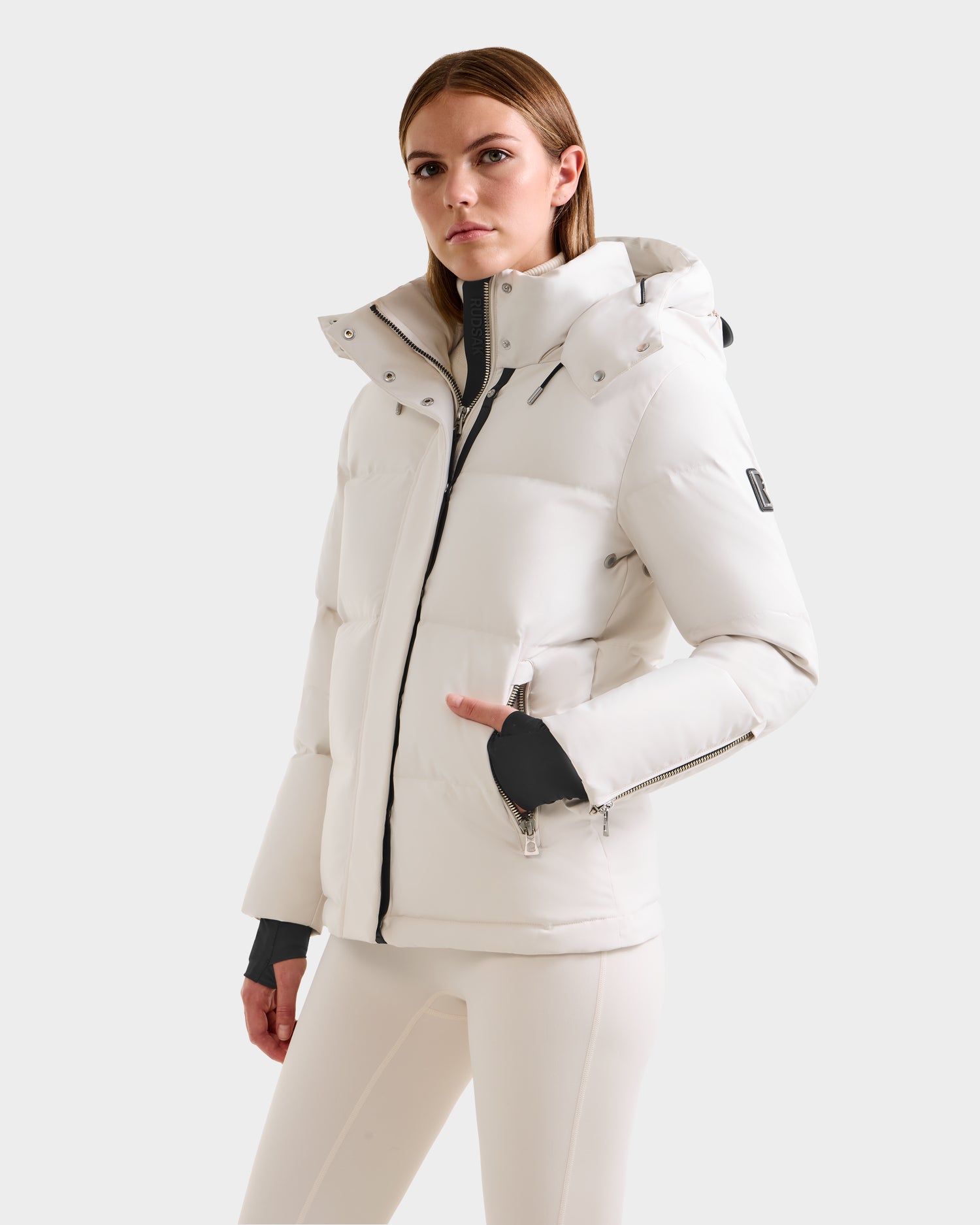 A woman models the Rudsak JOON H - 8125586 Vanilla insulated jacket and matching pants, standing against a plain light background and looking confidently at the camera with one hand in her jacket pocket.