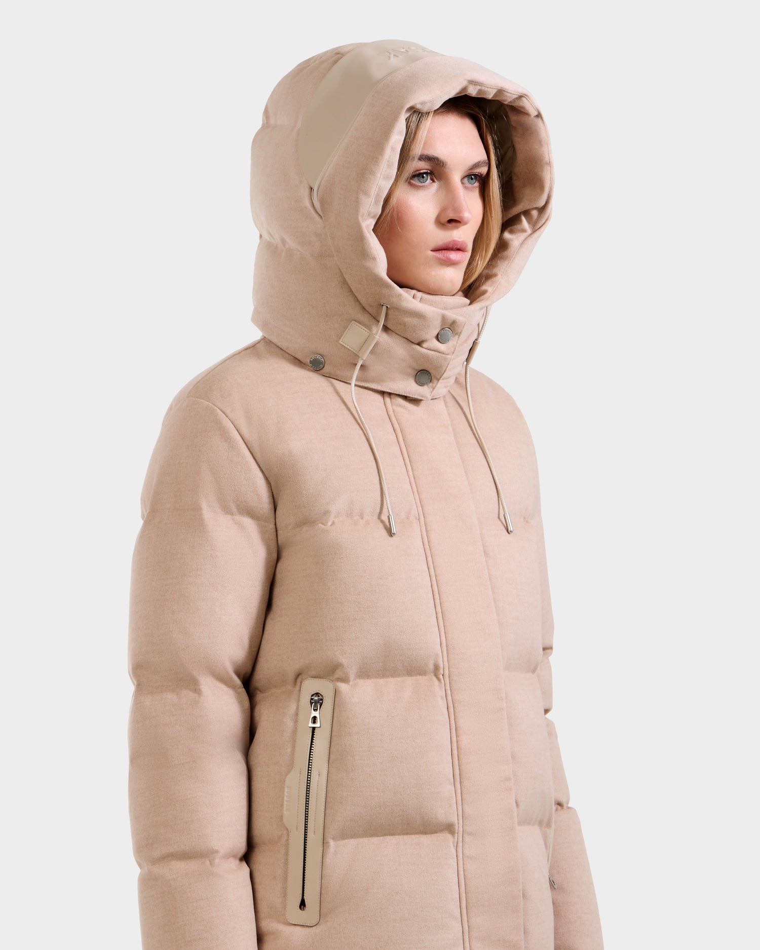 A person wears the Rudsak JOON W - 8125566 Heather Beige quilted winter coat with a hood and zippered side pockets, looking ahead with a neutral expression against a plain background.