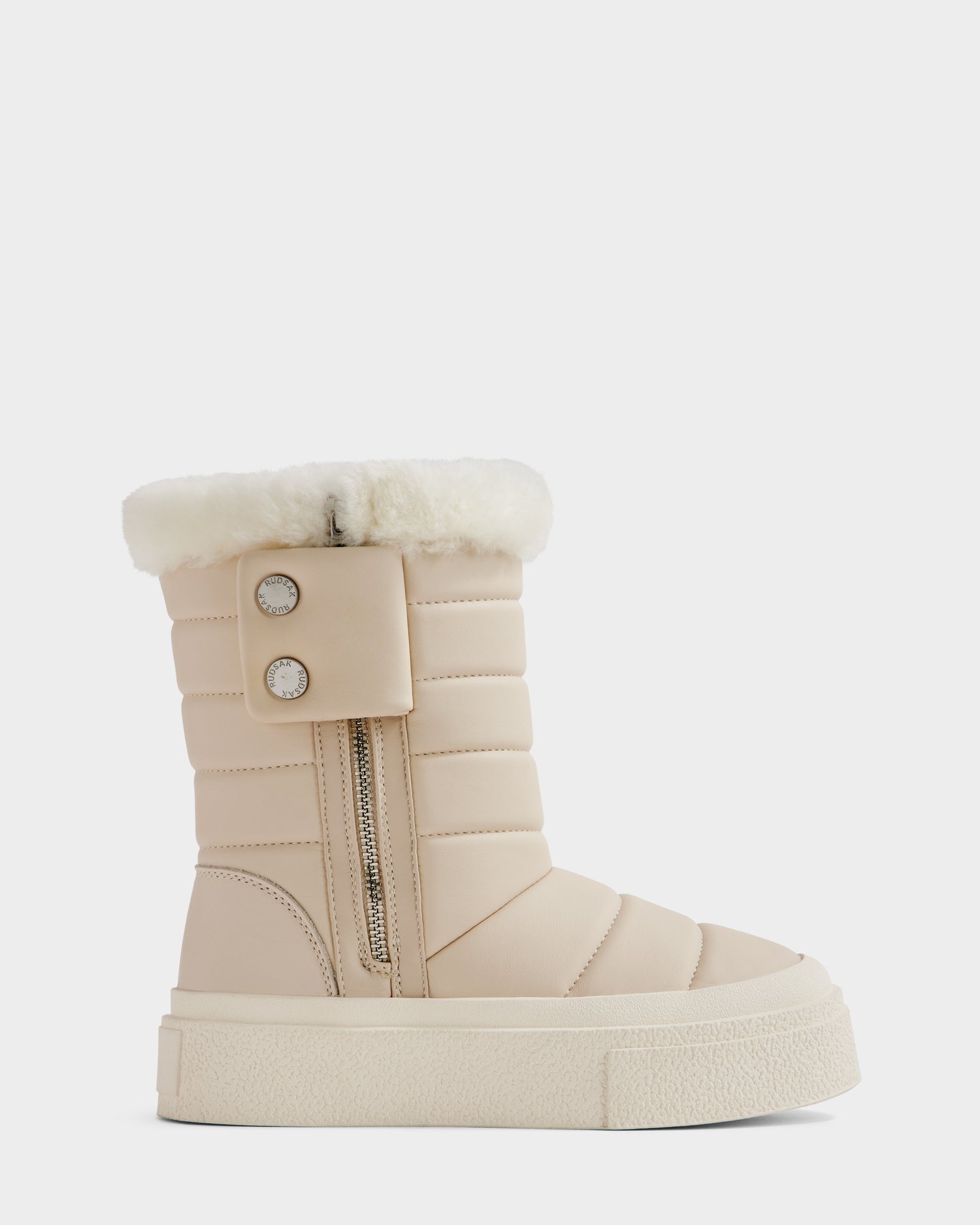 The Rudsak KATHIE - L225516 Vanilla is a beige women's mid boot in vegan leather with padded design, thick white sole, inner side zipper, buttoned flap, and fluffy white faux-fur trim, shown in side profile on a plain background.