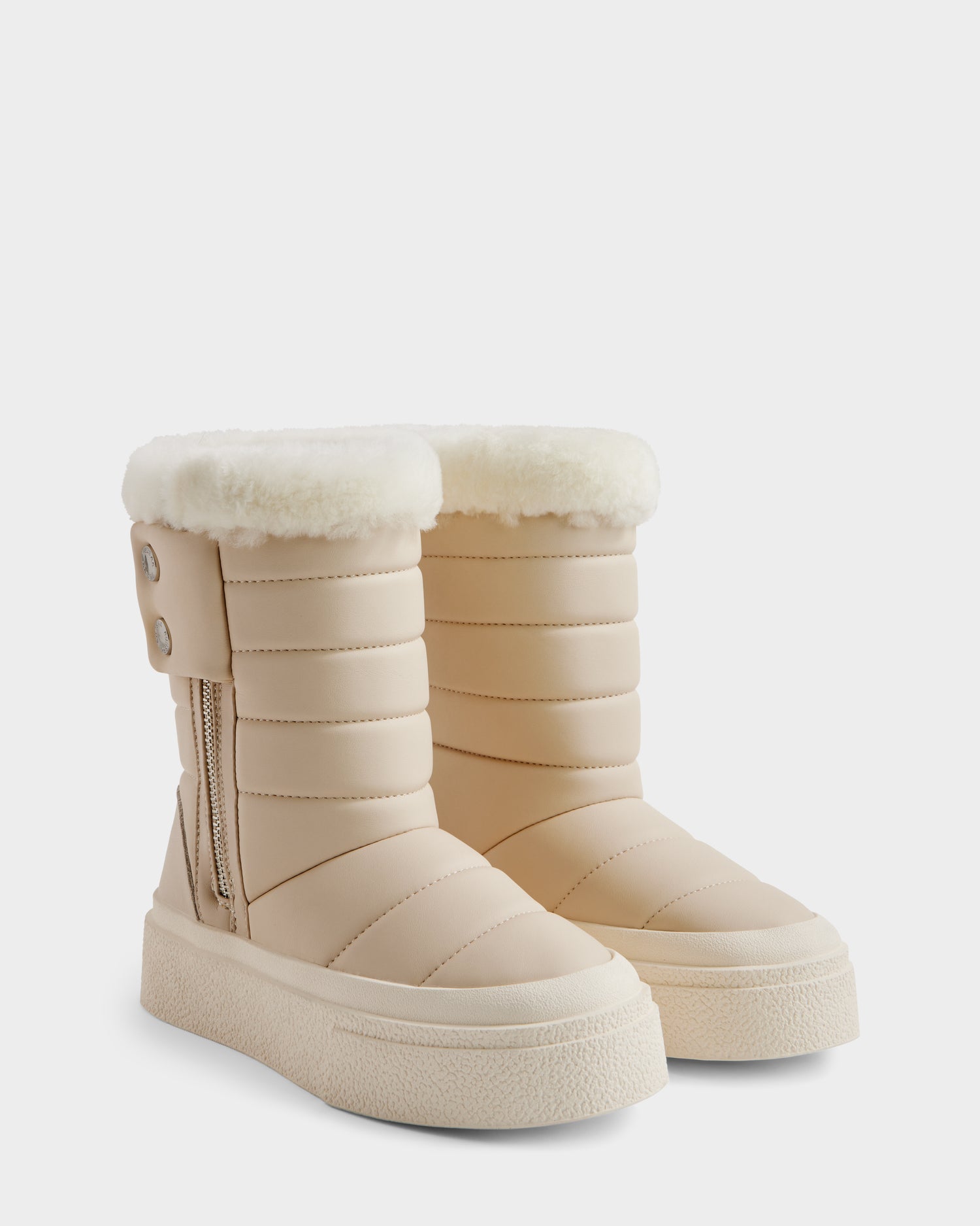 The KATHIE - L225516 Vanilla by Rudsak are beige quilted women’s mid boots with white faux fur lining, side zippers, decorative buttons, and thick textured soles. These stylish winter boots are shown on a plain white background.