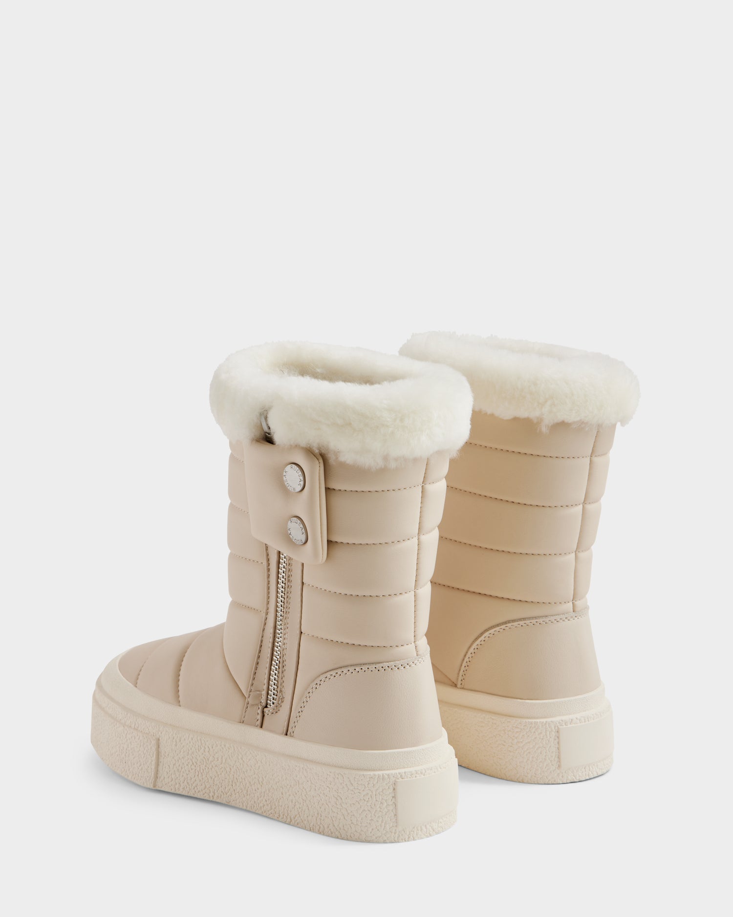 The Rudsak KATHIE - L225516 Vanilla are beige quilted women’s mid boots with white faux fur lining, side zippers, two outer decorative buttons, and thick textured rubber soles. Shown against a white background.