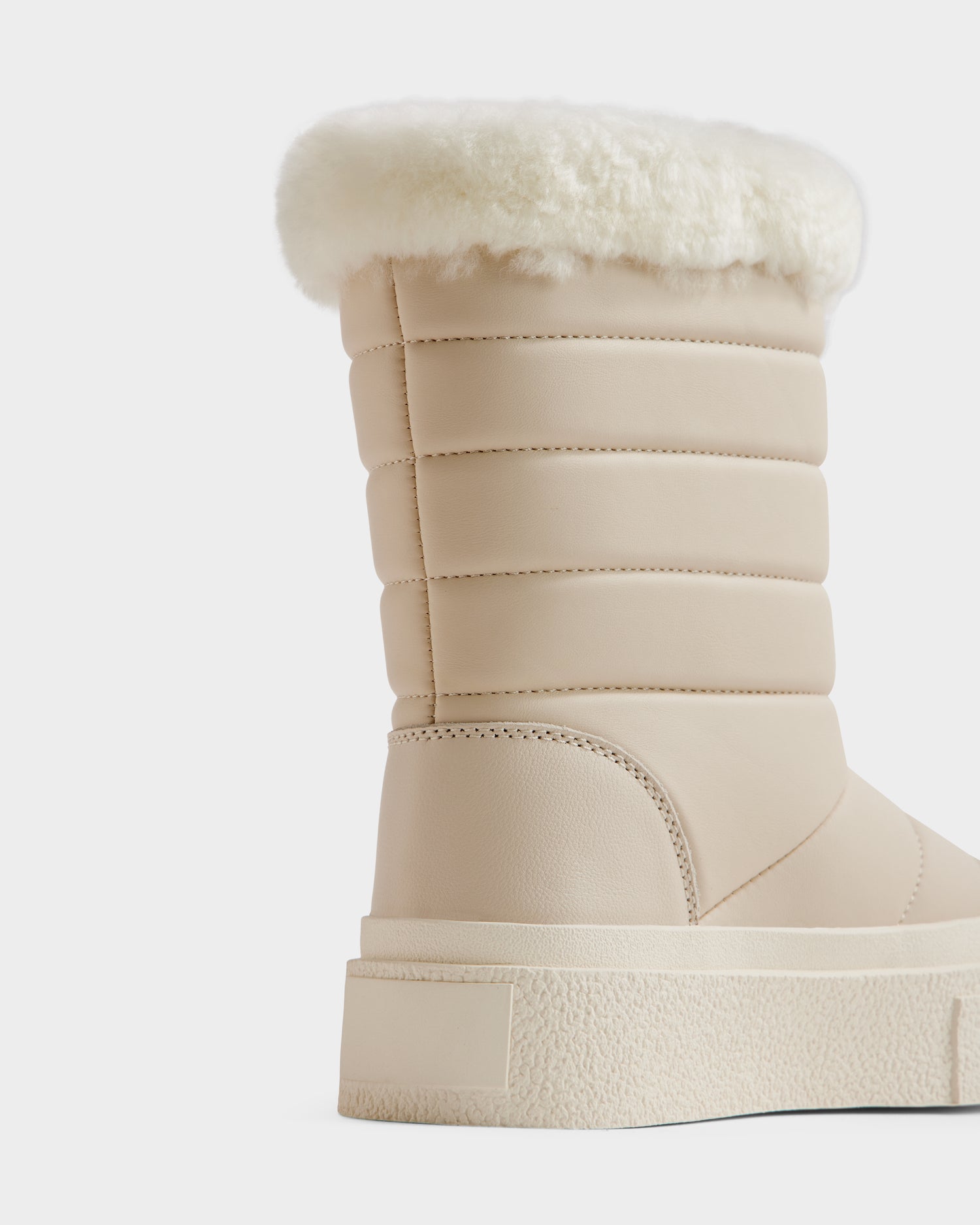 A close-up of Rudsak's KATHIE - L225516 Vanilla, a beige women’s mid boot in vegan leather with a thick rubber sole, quilted stitching, and fluffy white faux fur lining, shown against a plain white background.