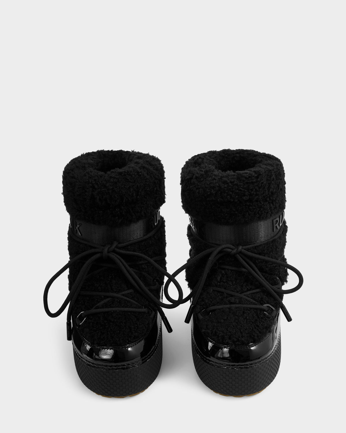 A pair of Rudsak KATHY Y - 1224500 Black water-repellent winter boots with textured fuzzy uppers, shiny black toe caps, thick soles, and black laces, viewed from the front against a plain white background.