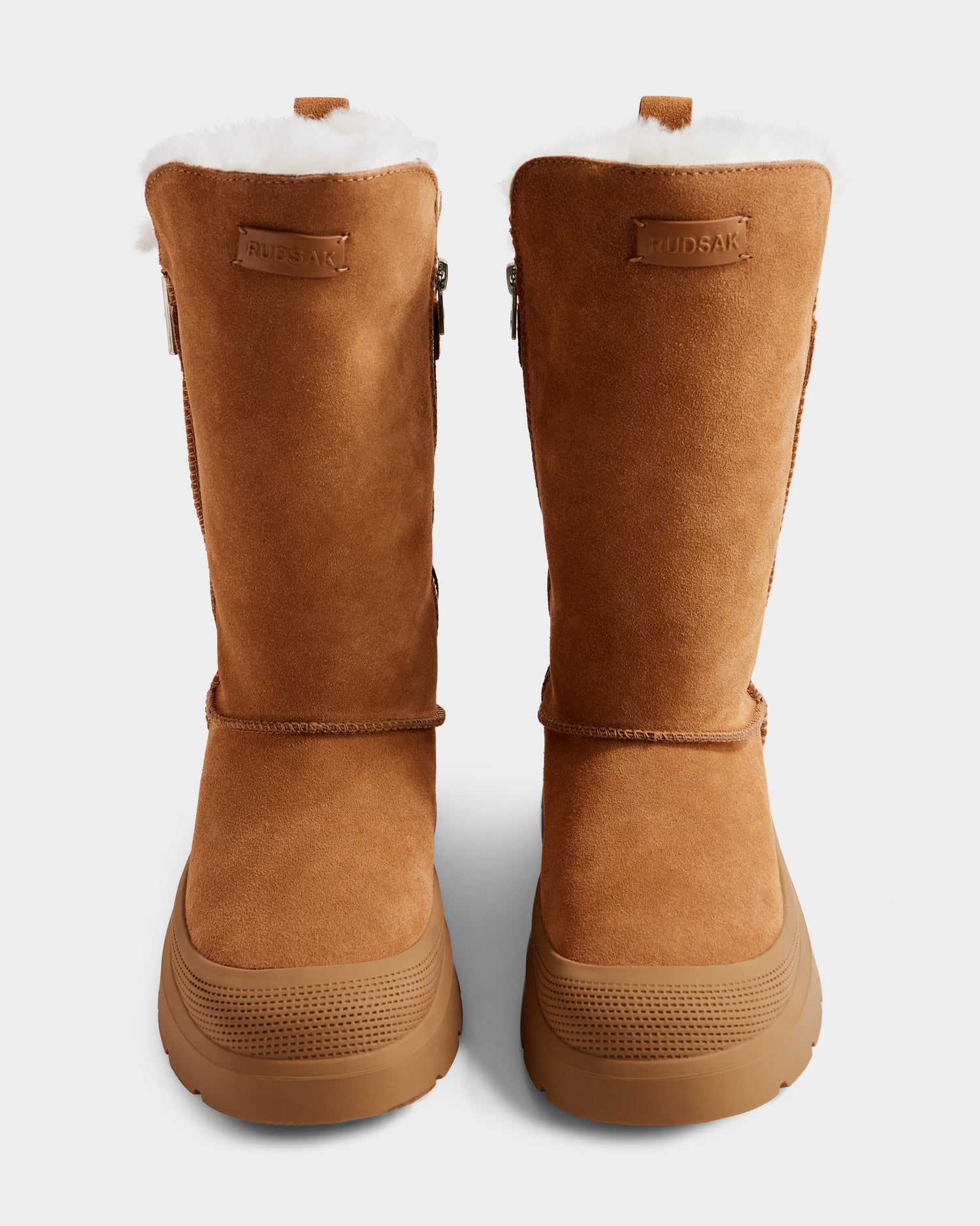 Rudsak KLAIR - L225027 Tan women’s suede winter boots feature white fleece lining, thick rubber soles, and front RUDSAK branding. These mid boots are shown upright against a plain background.