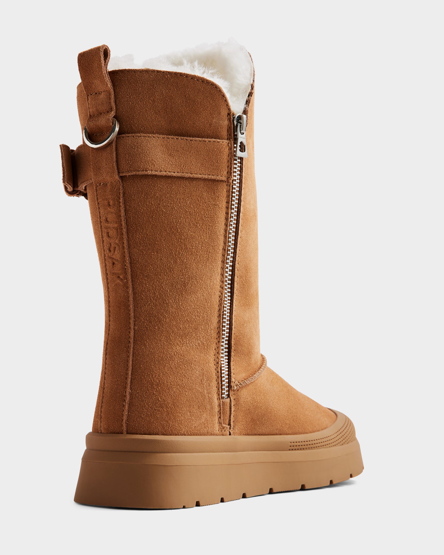 The KLAIR - L225027 Tan by Rudsak is a women’s tan suede mid-calf winter boot with plush white fleece lining, thick rubber sole, visible side zipper, and a decorative pull tab—ideal wool-lined boots for cozy style.
