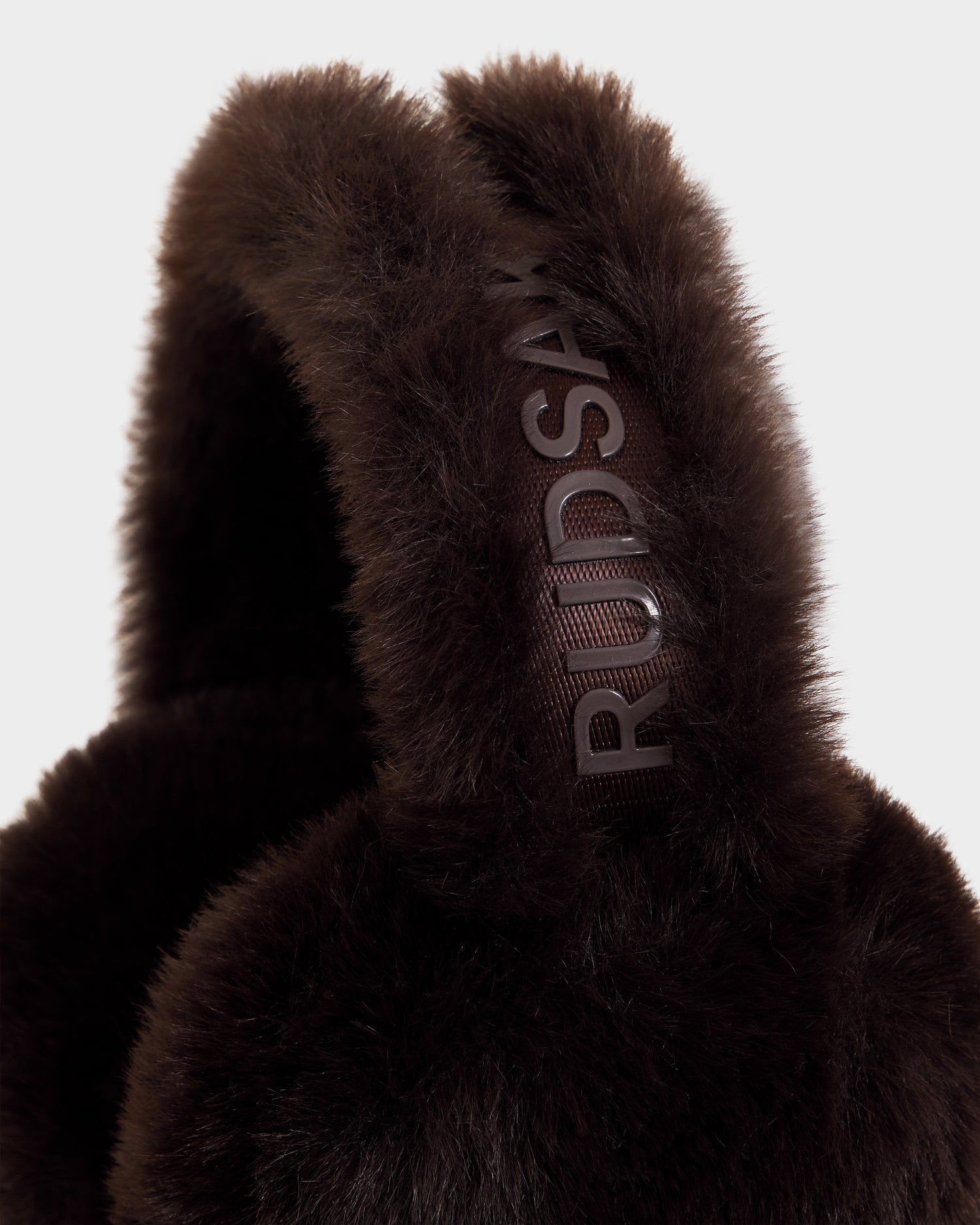 Close-up of the LAINA F - L423501 Espresso dark brown faux fur earmuffs by Rudsak, featuring the brand name on the headband—a cozy must-have for your winter accessories collection.