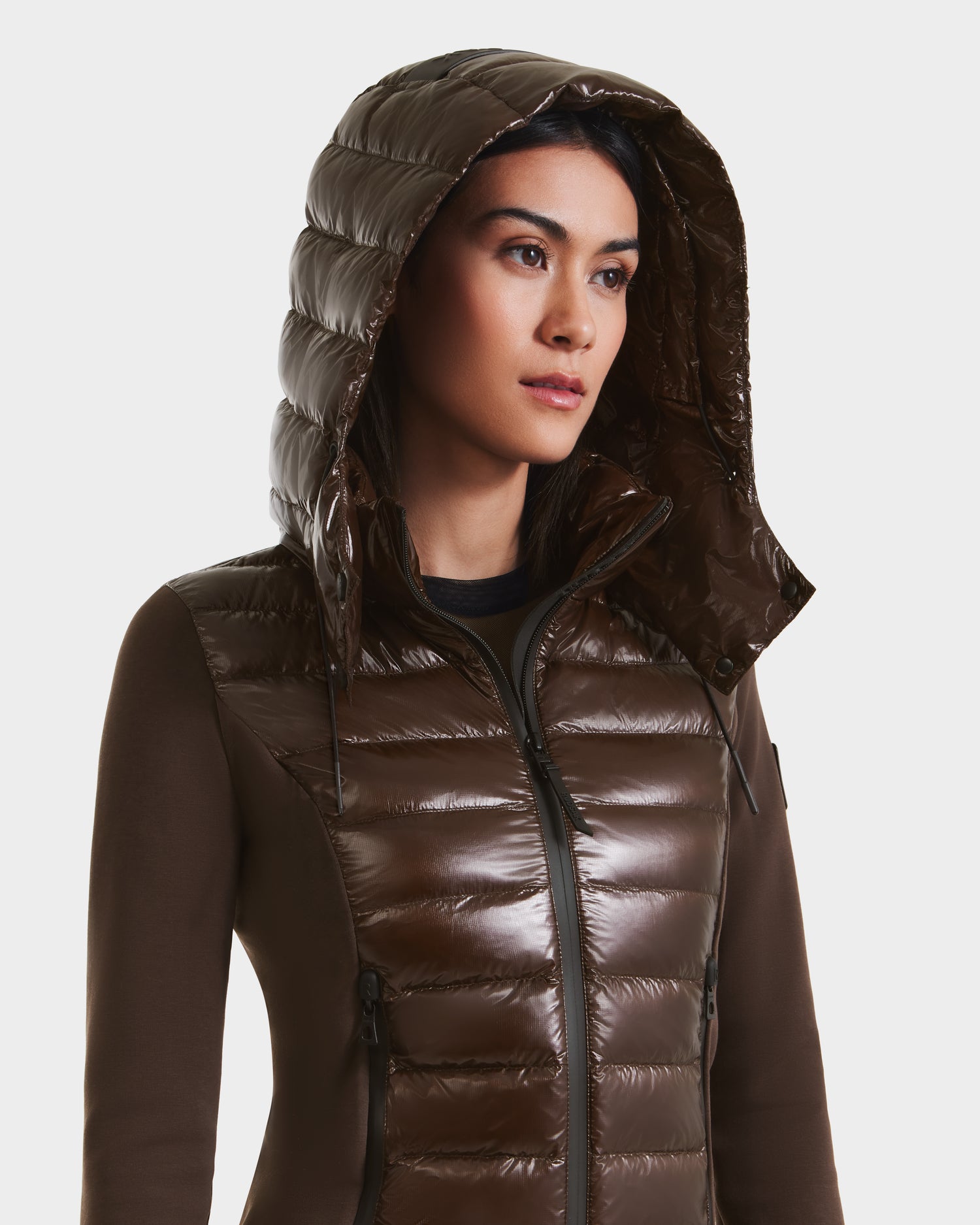 A woman wearing the Rudsak MABS C - 8124590 Espresso glossy dark brown puffer jacket with RDS-certified down and hood up, looking slightly to the side against a plain white background.