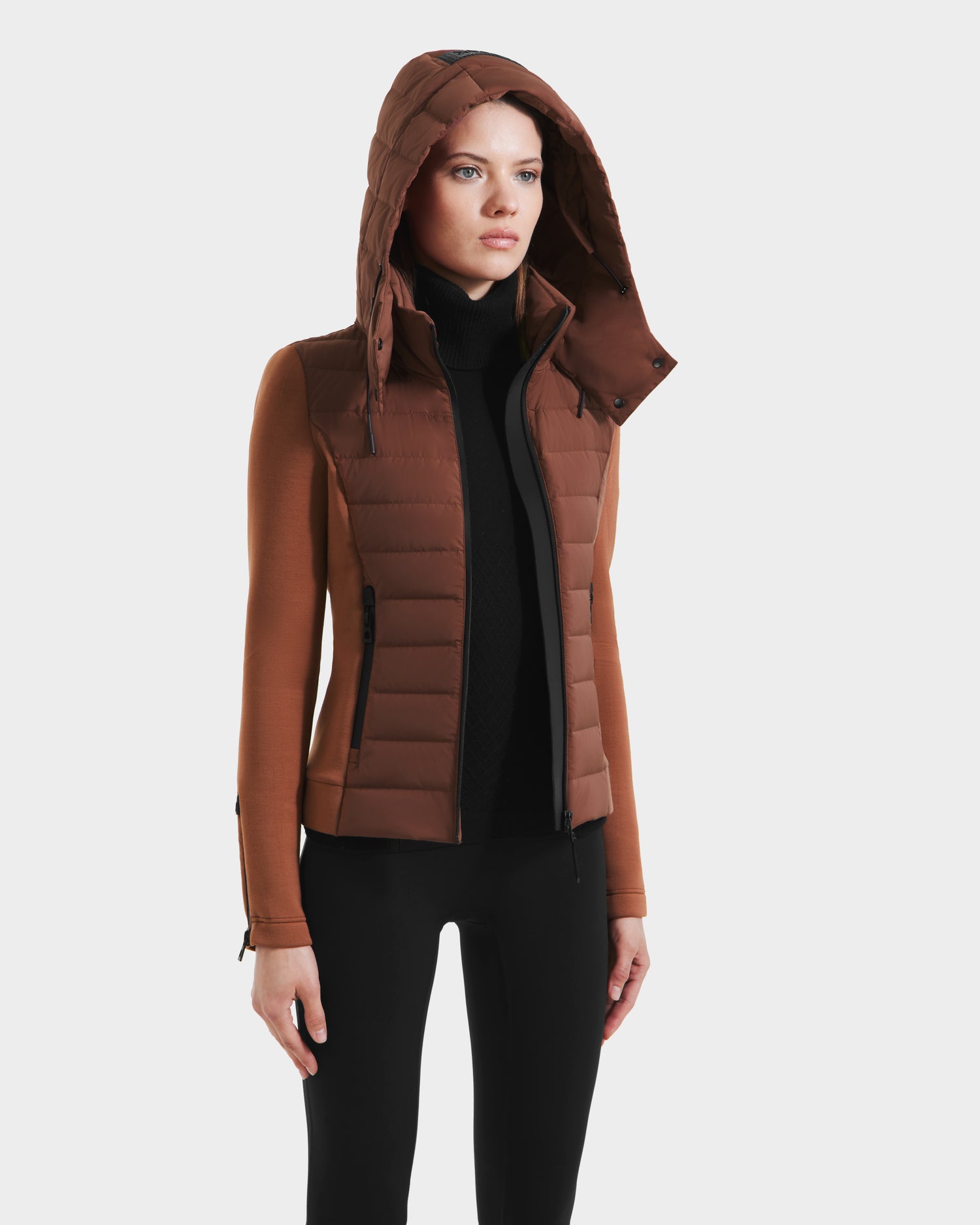 A woman wears the Rudsak MABS - 8125055 Rust women’s puffer jacket with black sleeves and black pants, standing against a plain white background.