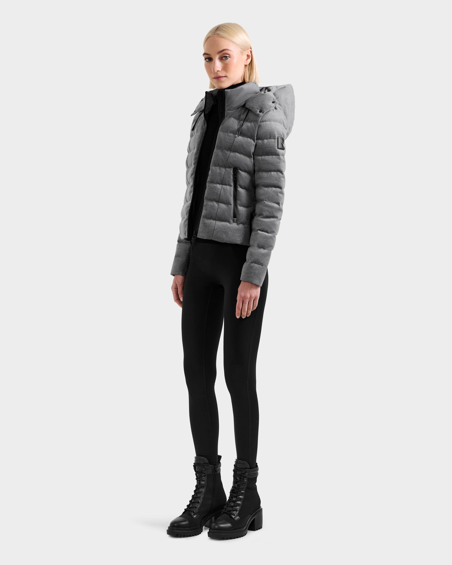A person wears the Rudsak MELISSA W - 8125564 Heather Charcoal down jacket with black leggings and black lace-up boots, standing forward against a plain light background.