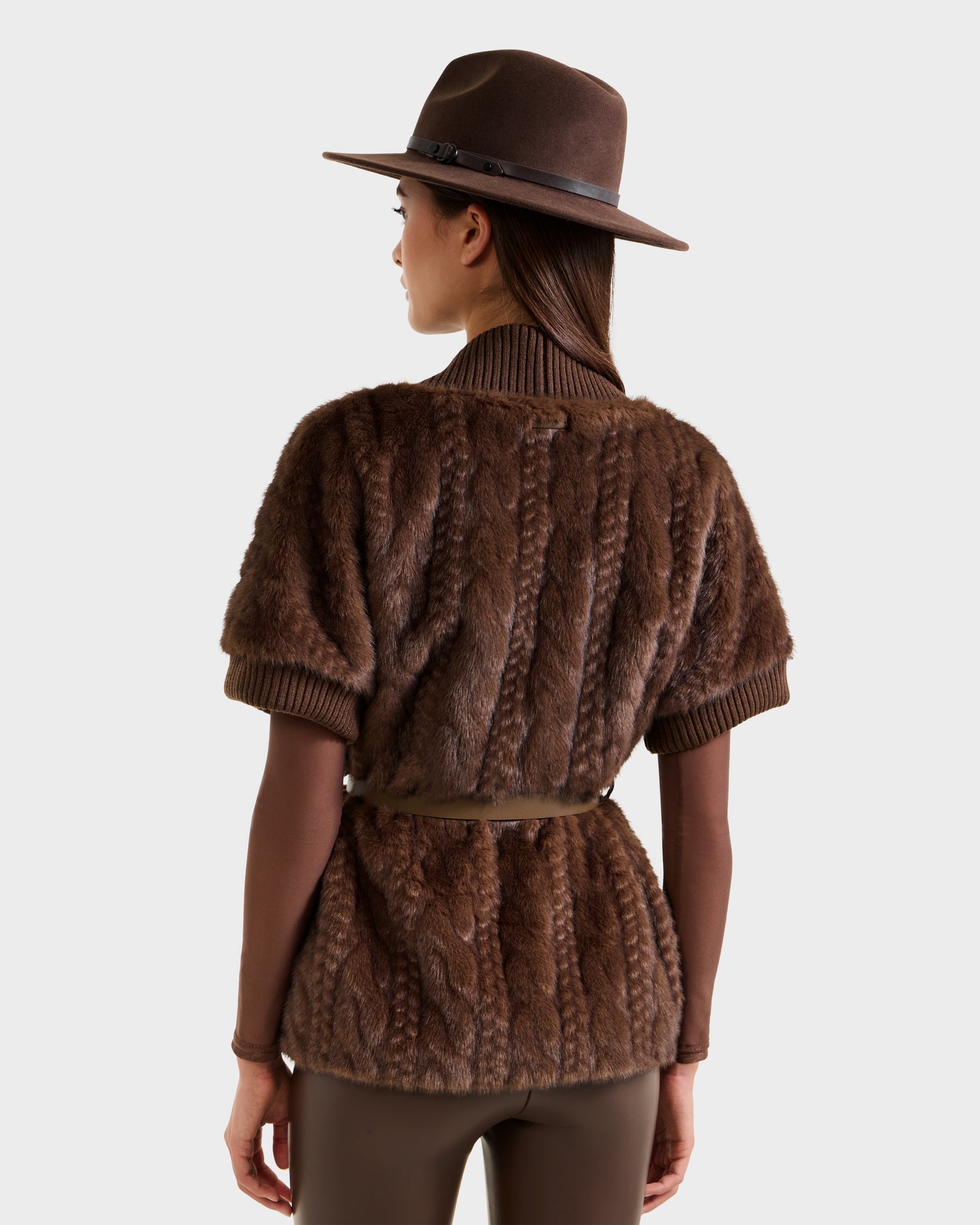 A person wearing the Rudsak MENDOTA F - 8525561 Mocha faux fur top, along with a brown hat and pants, stands facing away from the camera against a plain white background.