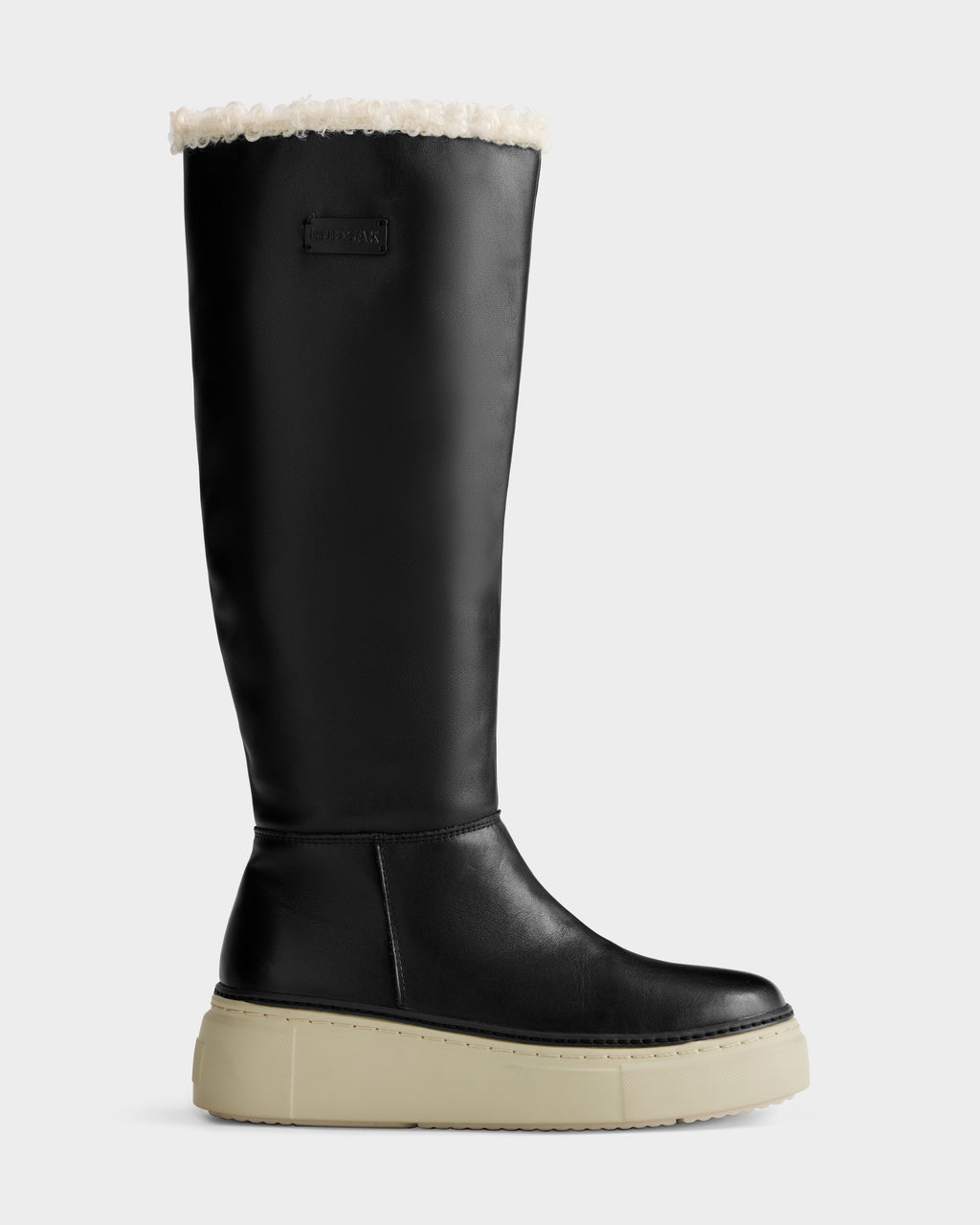 The Rudsak MIKIE L - 8225580 Black boot features a tall black silhouette, cream fuzzy lining at the top, and a thick light beige platform sole, shown in profile against a plain background.