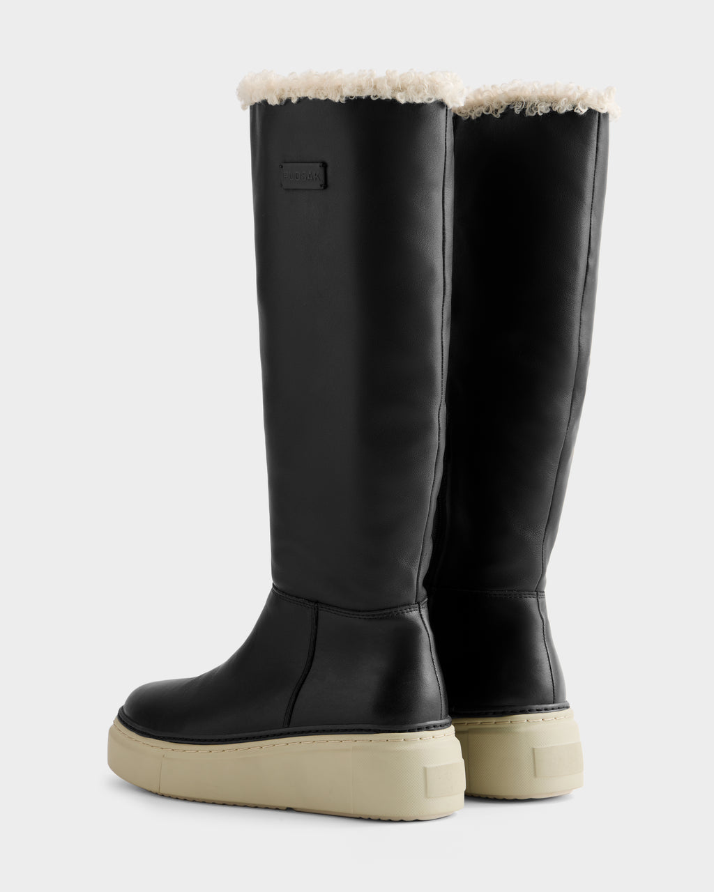 MIKIE L - 8225580 Black boots by Rudsak feature tall black uppers, beige platform soles, and white faux fur lining visible at the top, shown from the back and side against a plain light background.