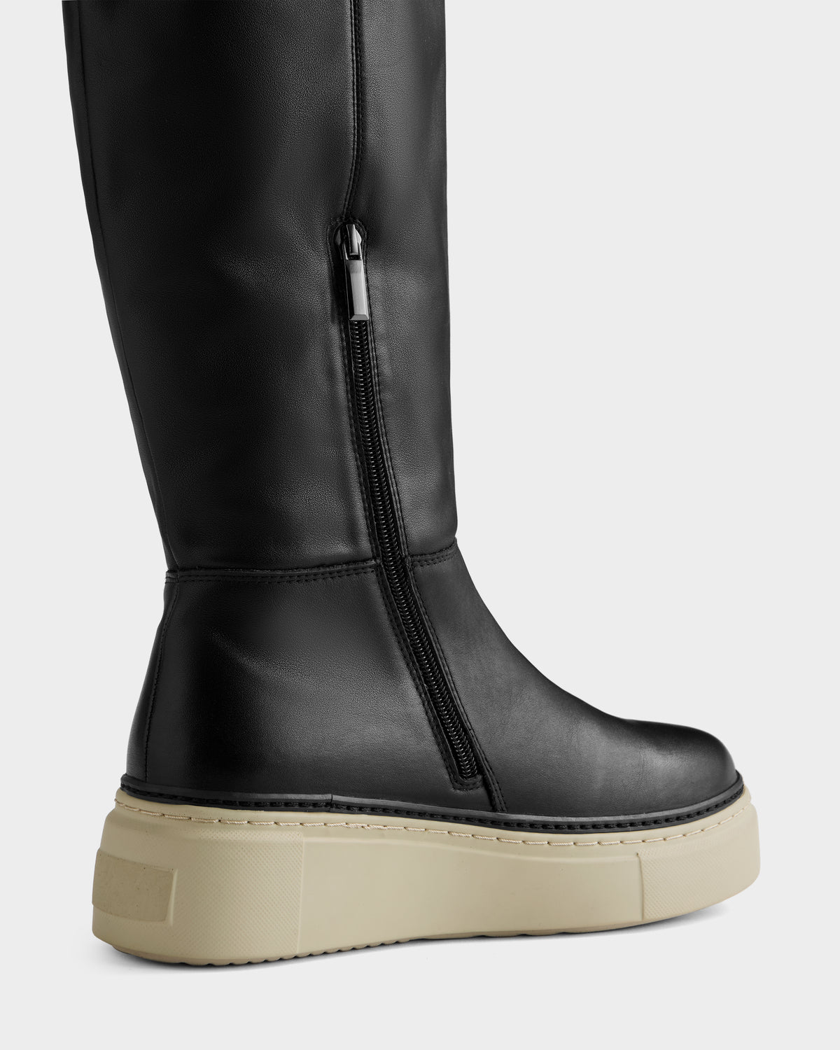 A close-up of the Rudsak MIKIE L - 8225580 Black knee-high boot features a side zipper and thick light beige platform sole, set against a plain light background.