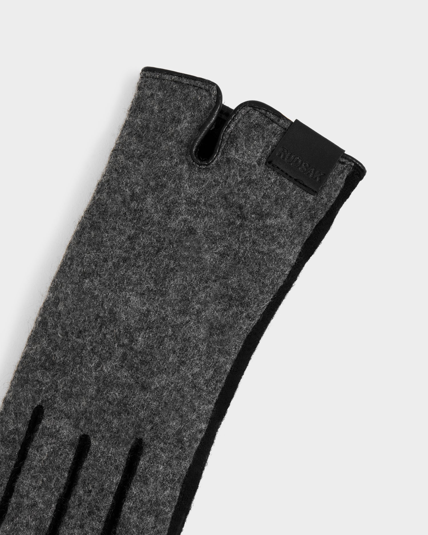 A close-up of the OLGA - L425541 Grey women’s glove by Rudsak, featuring gray felt, black trim, a leather cuff tag, and a cozy wool-cashmere lining—an elegant cold-weather essential shown on a white background.