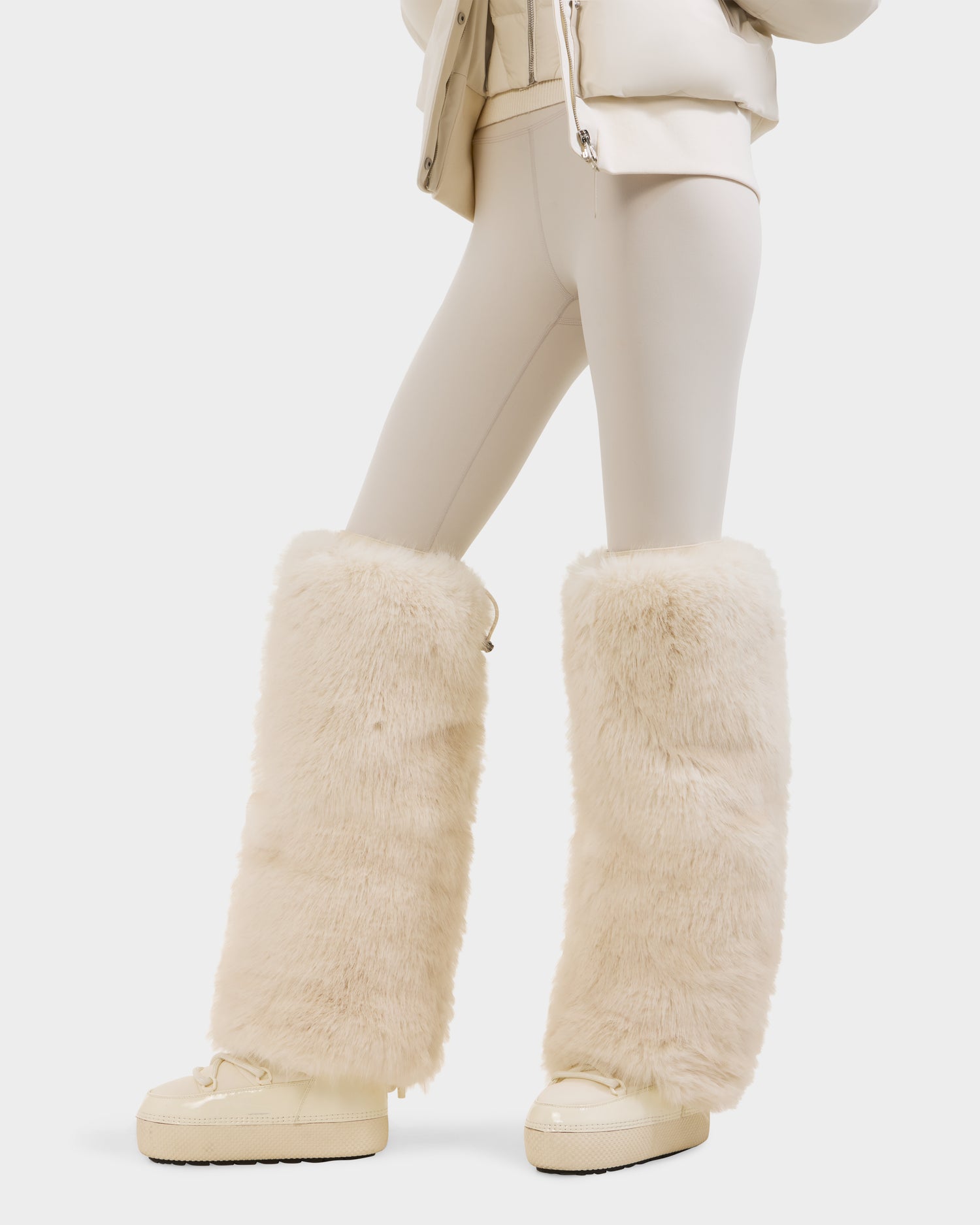 A person wears PAIGE - 8425534 Vanilla leggings by Rudsak, paired with matching shoes and large faux fur leg warmers, photographed from the waist down against a white background.