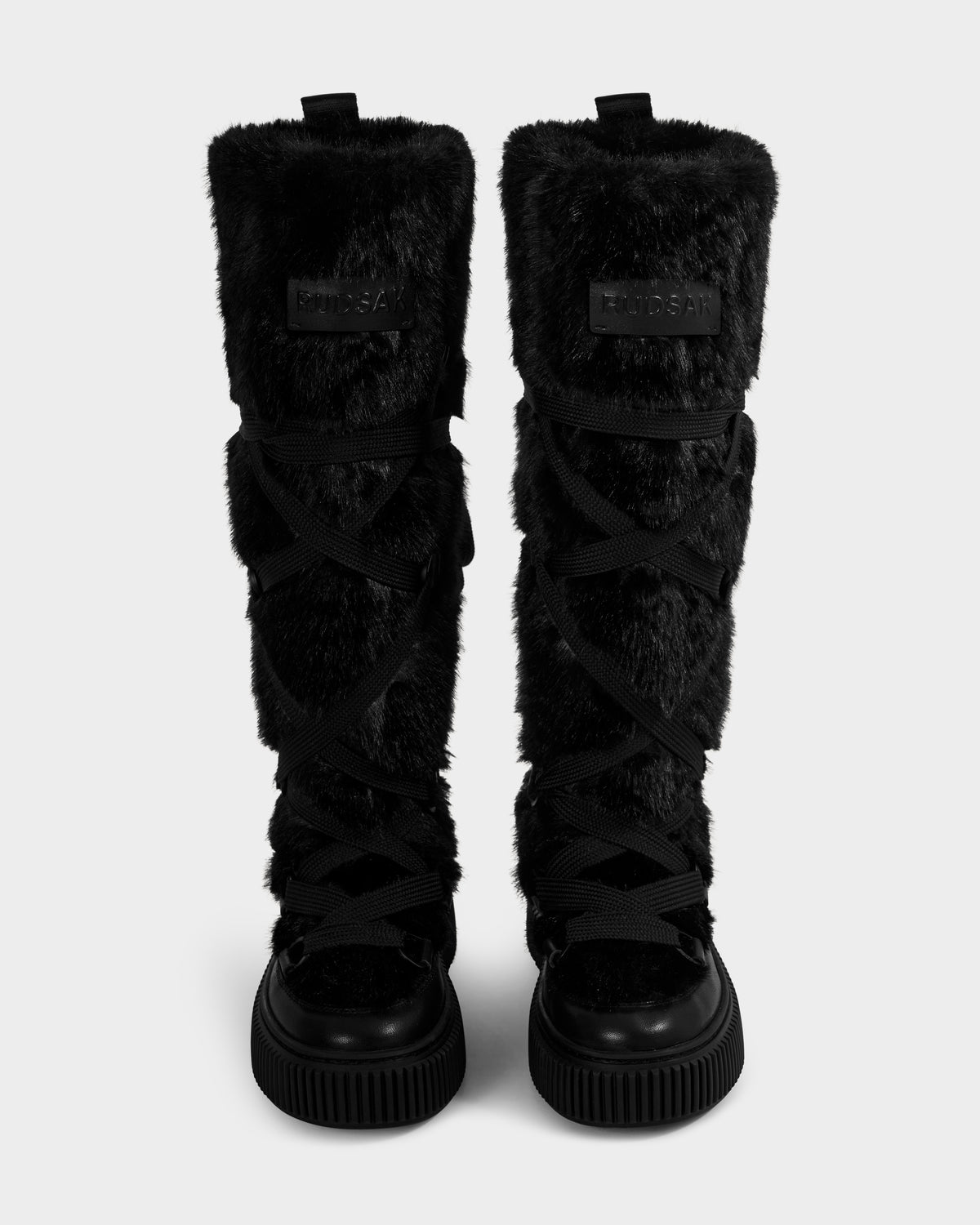 A pair of Rudsak PALERMO C - 8225546 black women’s faux fur winter boots with criss-cross laces and thick rubber soles, displayed facing forward on a plain light background—ideal for cozy, stylish winter wear.