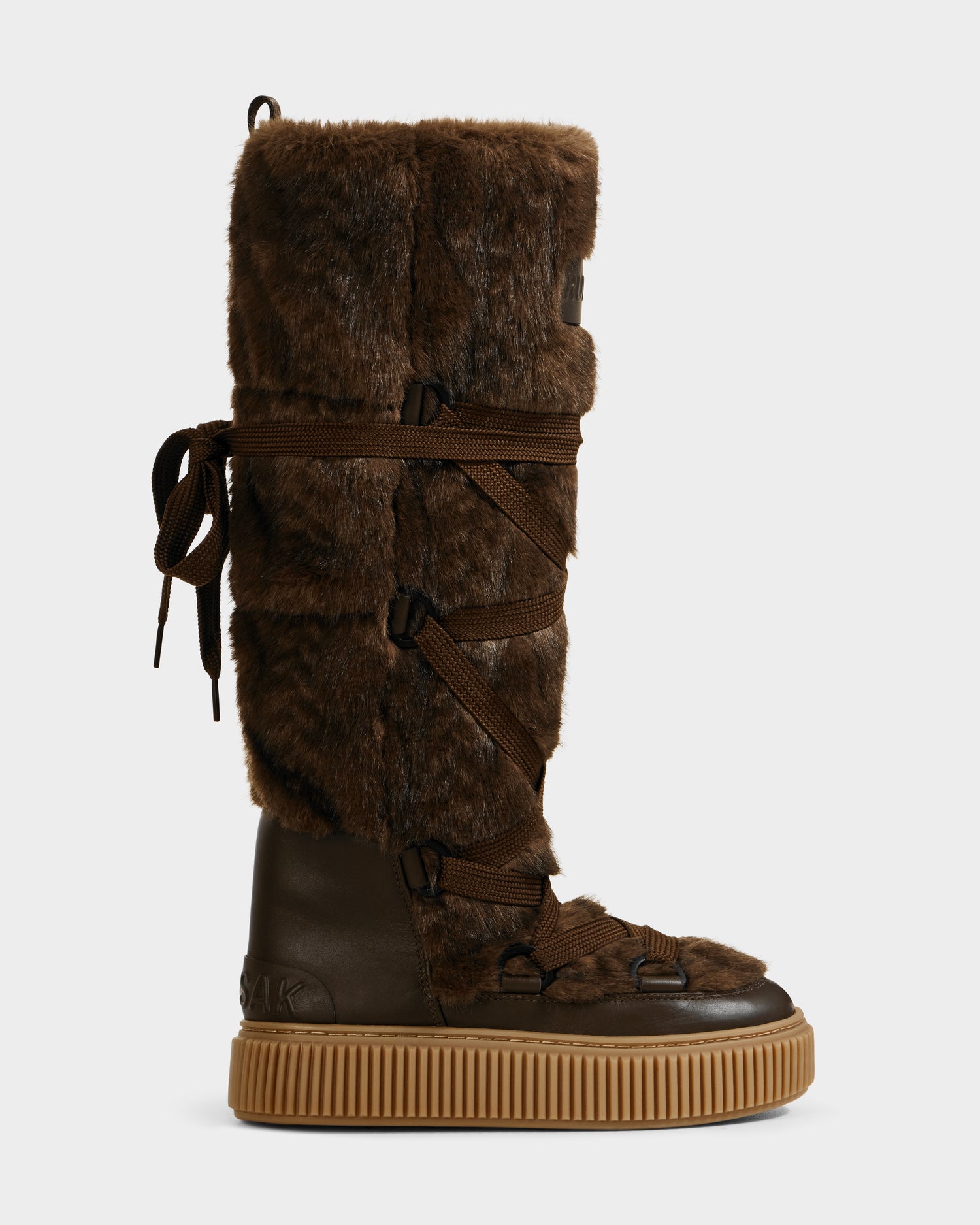 The Rudsak PALERMO C - 8225546 Mocha is a tall women’s winter boot with a brown faux fur upper, dark brown laces, a dark brown leather lower section, and a thick light brown rubber sole for après-ski style and warmth.