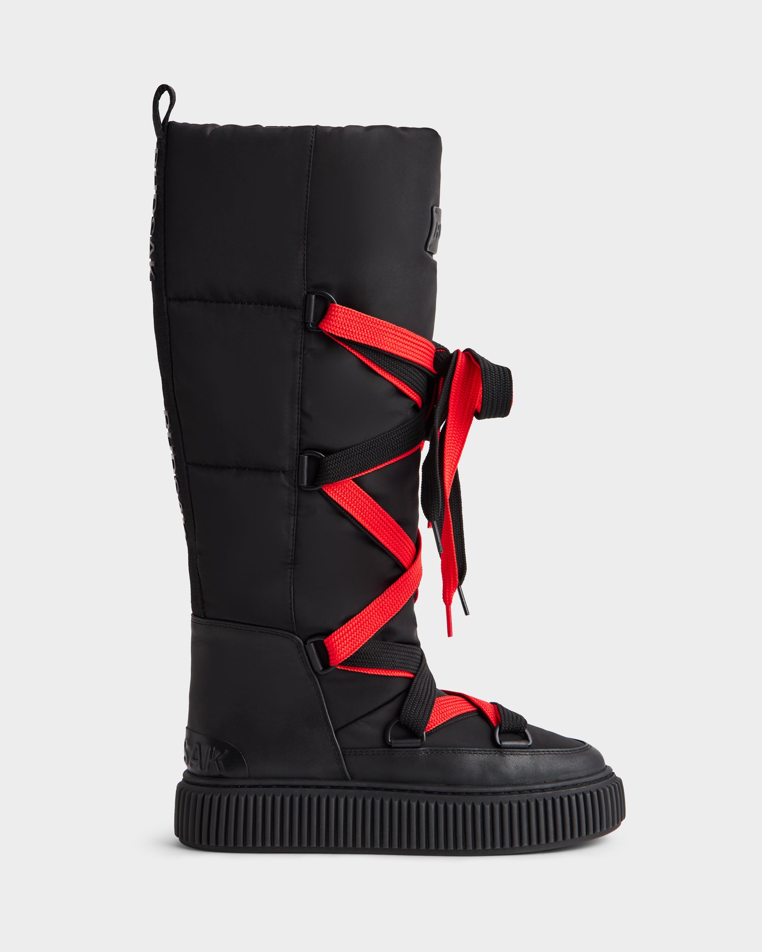 The Rudsak PALERMO - 8225030 Black is a tall women’s winter boot with red crisscross laces and a thick, ridged black sole, shown in side profile against a plain white background.