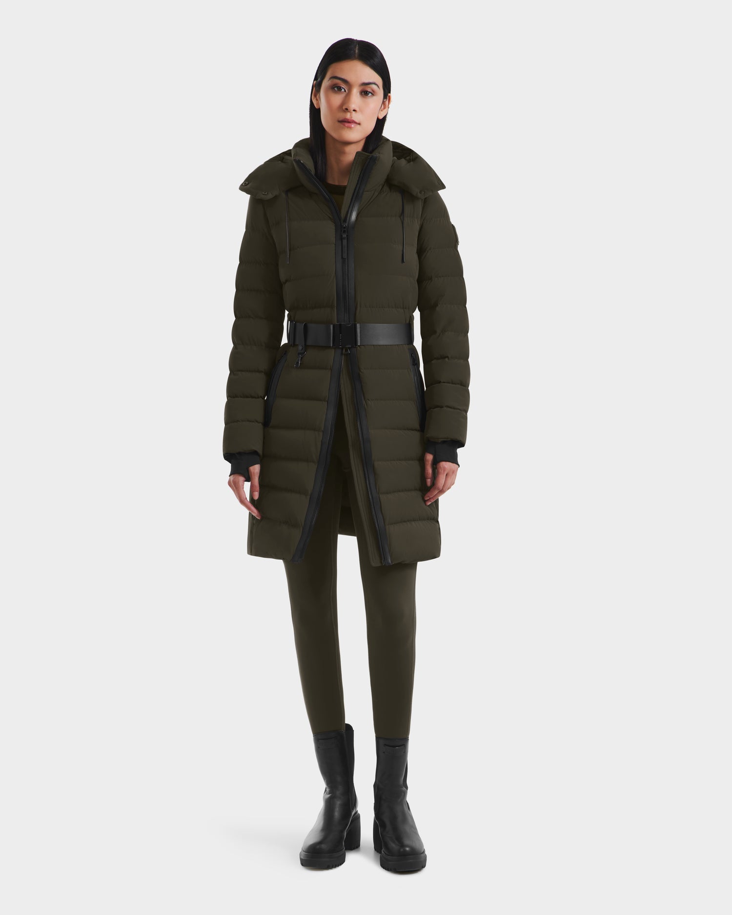 A woman faces forward in a Rudsak PELIN M - 8124814 Dark Olive RDS-certified down puffer coat, olive leggings, and black ankle boots against a plain white background.
