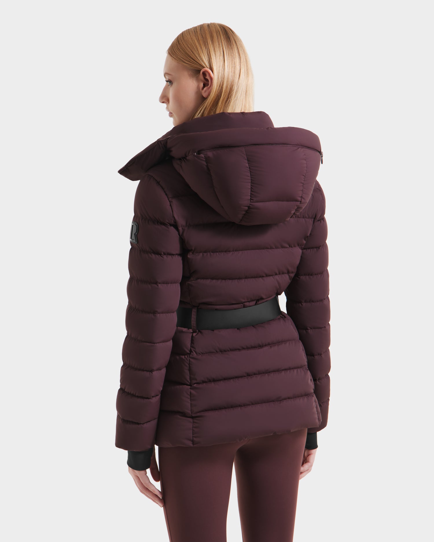 A woman stands confidently in the PELIN S - 8124813 Bordeaux by Rudsak, a quilted winter coat for women crafted from RDS-certified down for exceptional warmth and style.