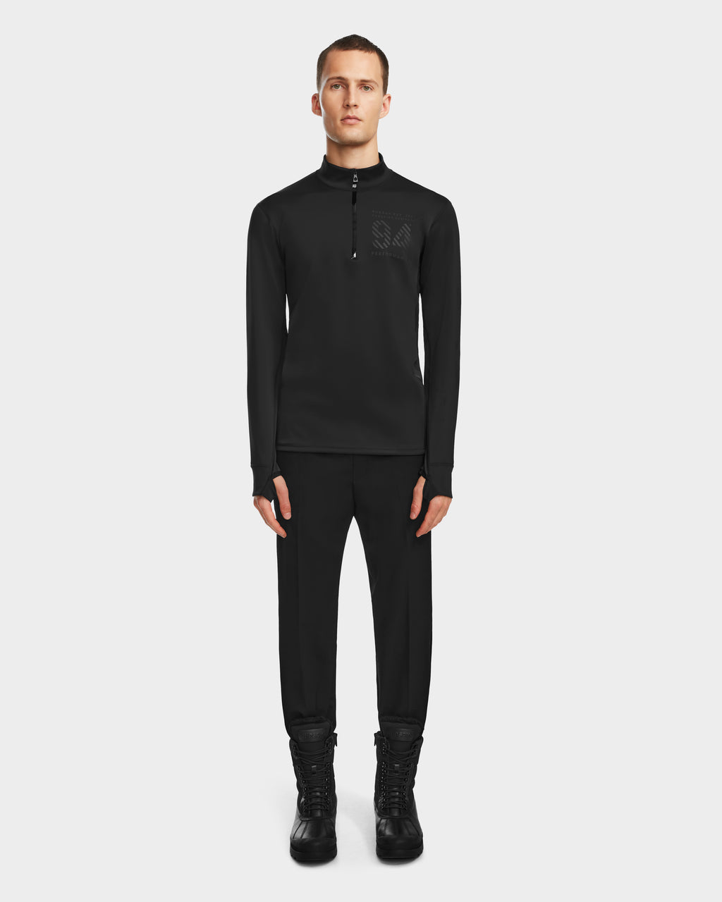 A man faces forward on a plain white background, wearing the RALI - 6524522 Black active top by Rudsak—perfect for winter sports layering—paired with matching black pants and boots.